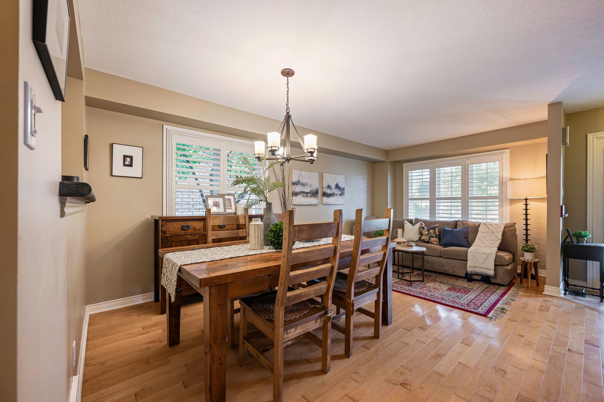 A dining room with a wooden table and chairs and a chandelier.