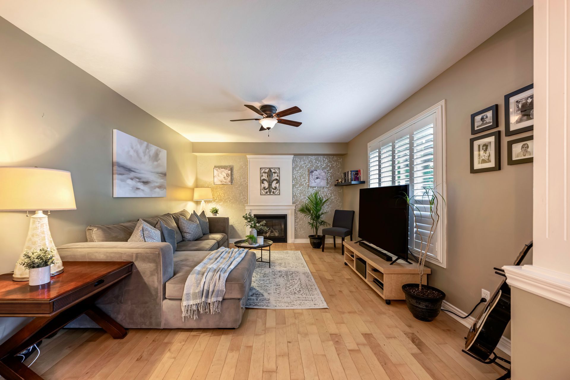 A living room with a couch , television , fireplace and ceiling fan.