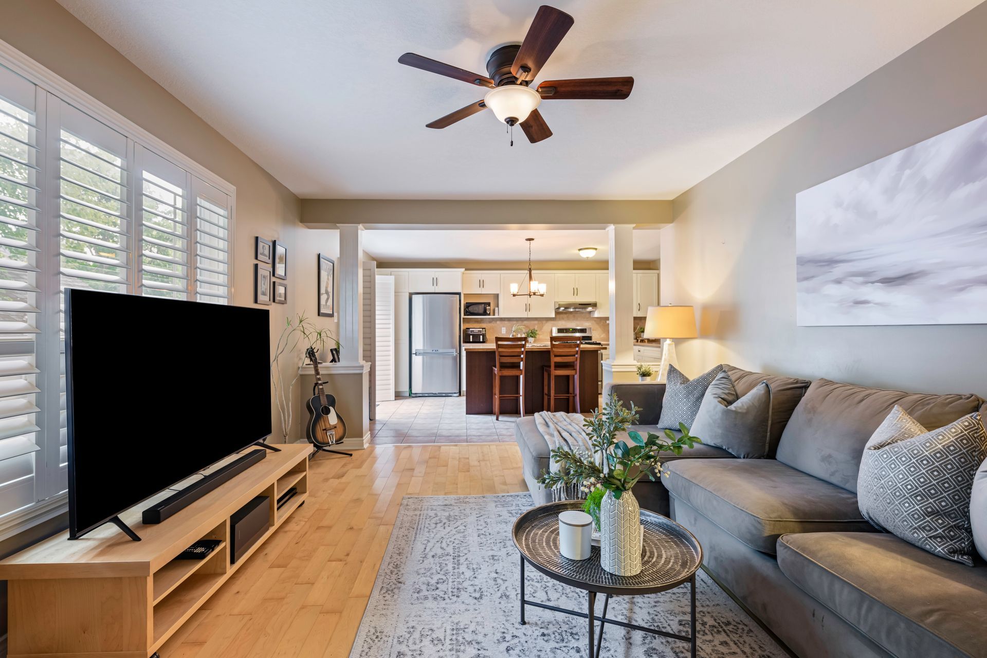 A living room with a couch , television , and ceiling fan.