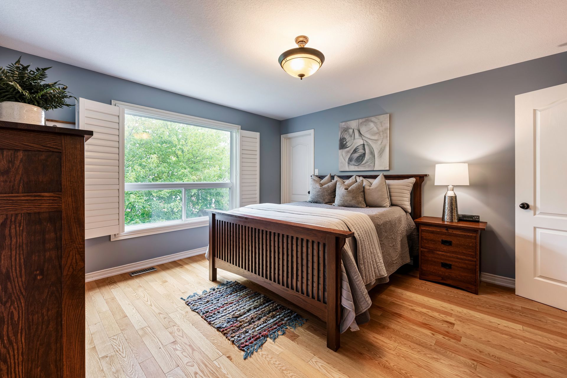 A bedroom with a bed , nightstand , dresser and window.