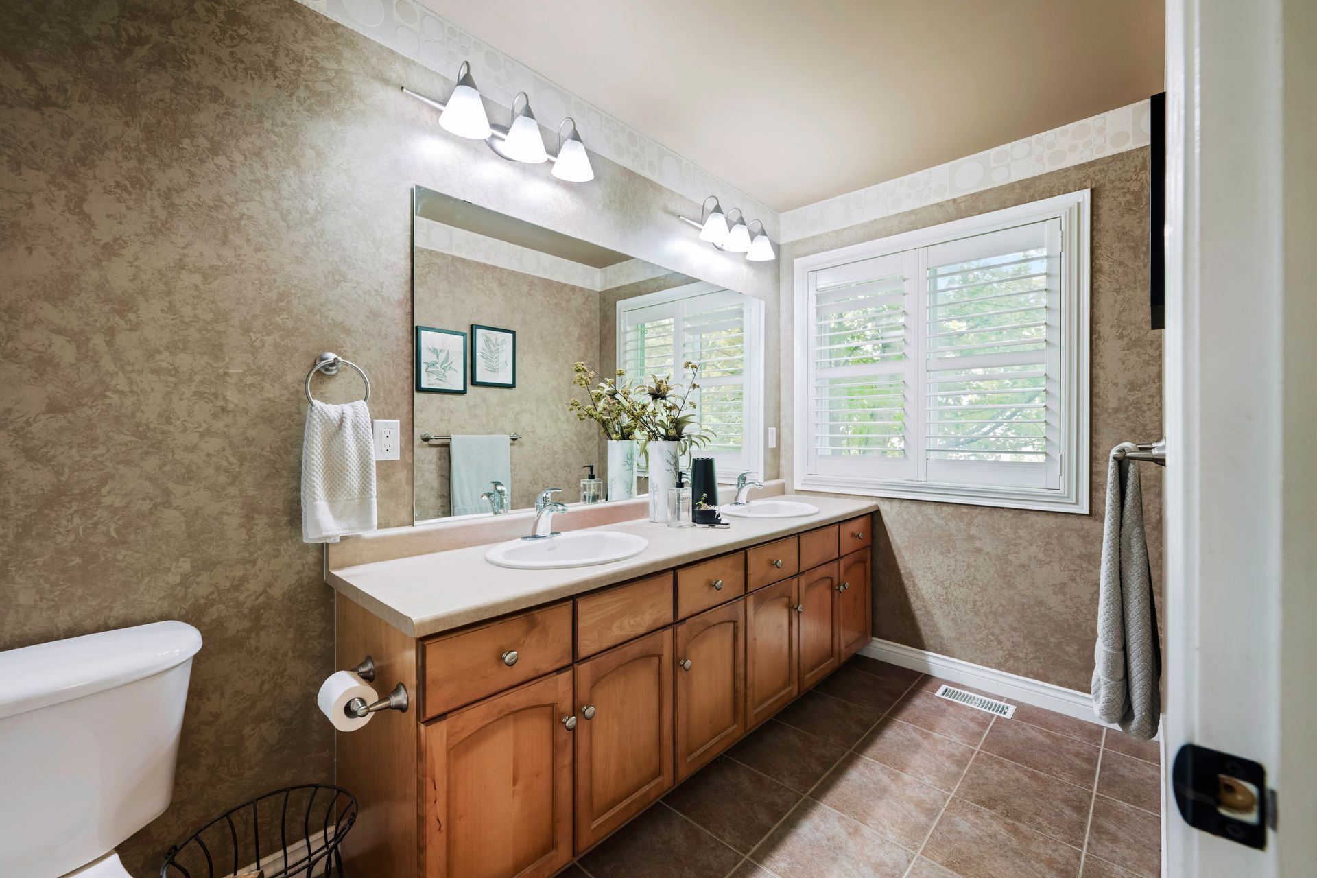 A bathroom with two sinks , a toilet , and a large mirror.