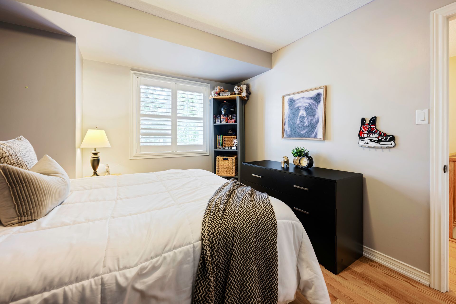 A bedroom with a bed , dresser , lamp and a picture on the wall.