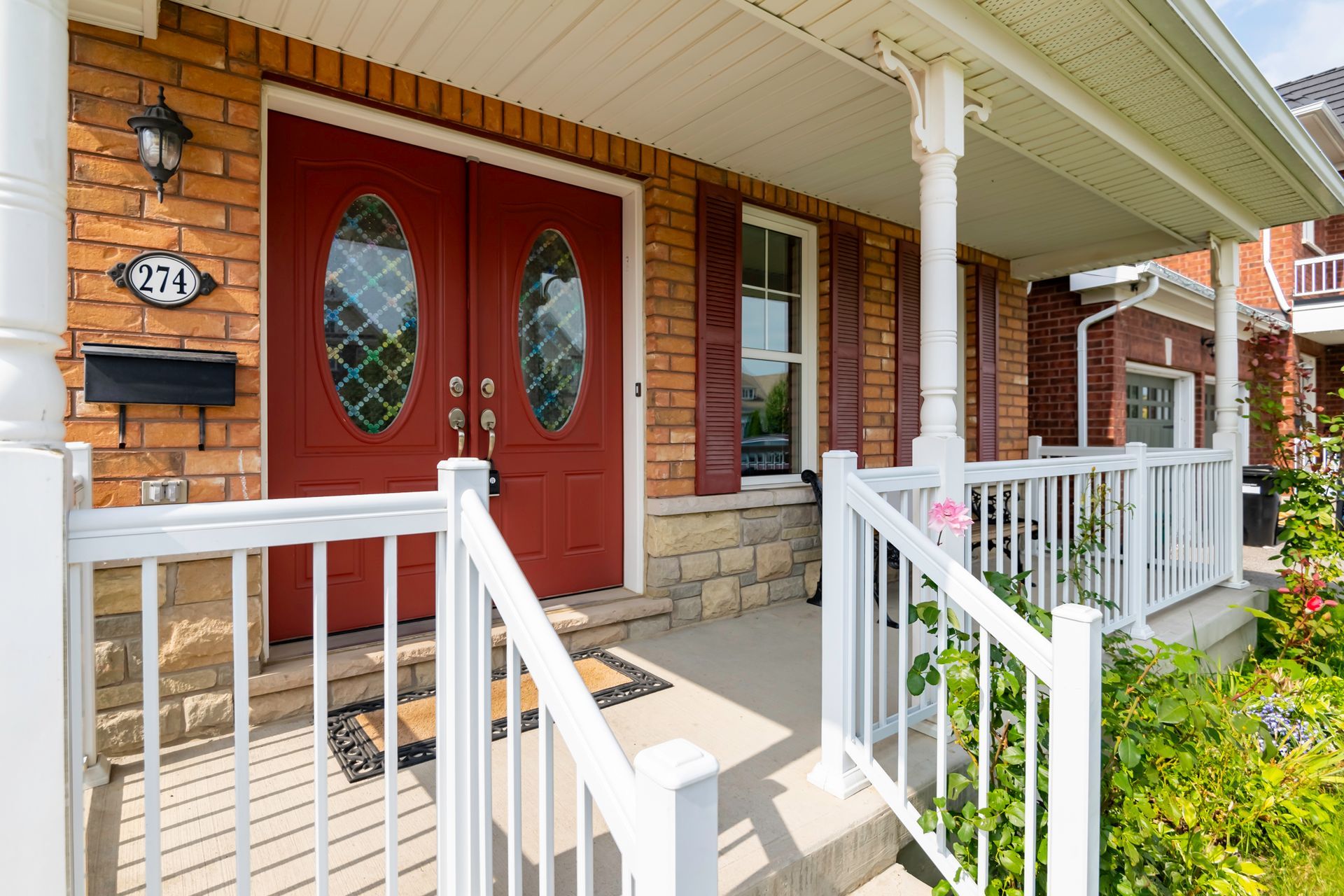 A brick house with a red door and a white railing