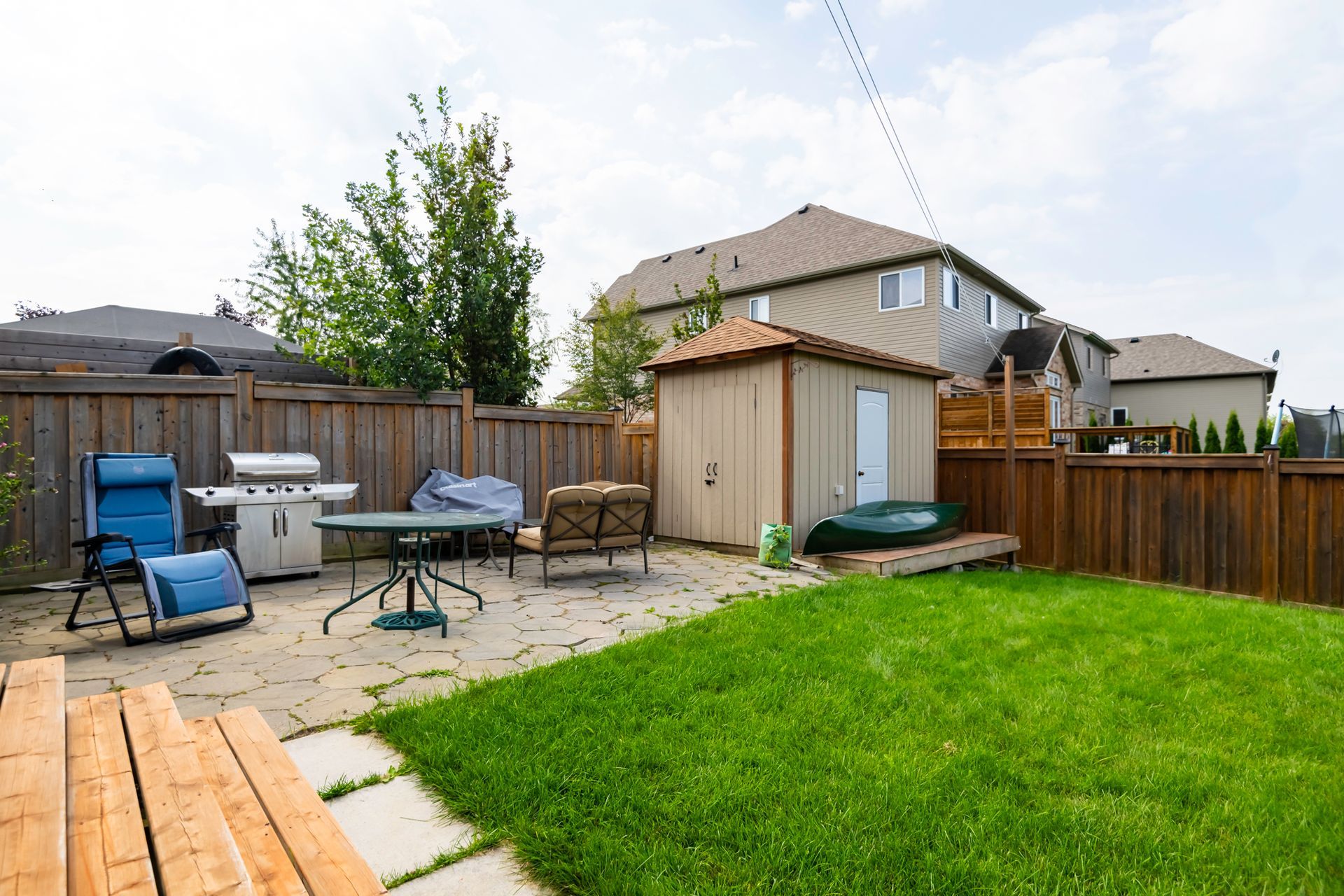 A backyard with a shed , table , chairs and a grill.