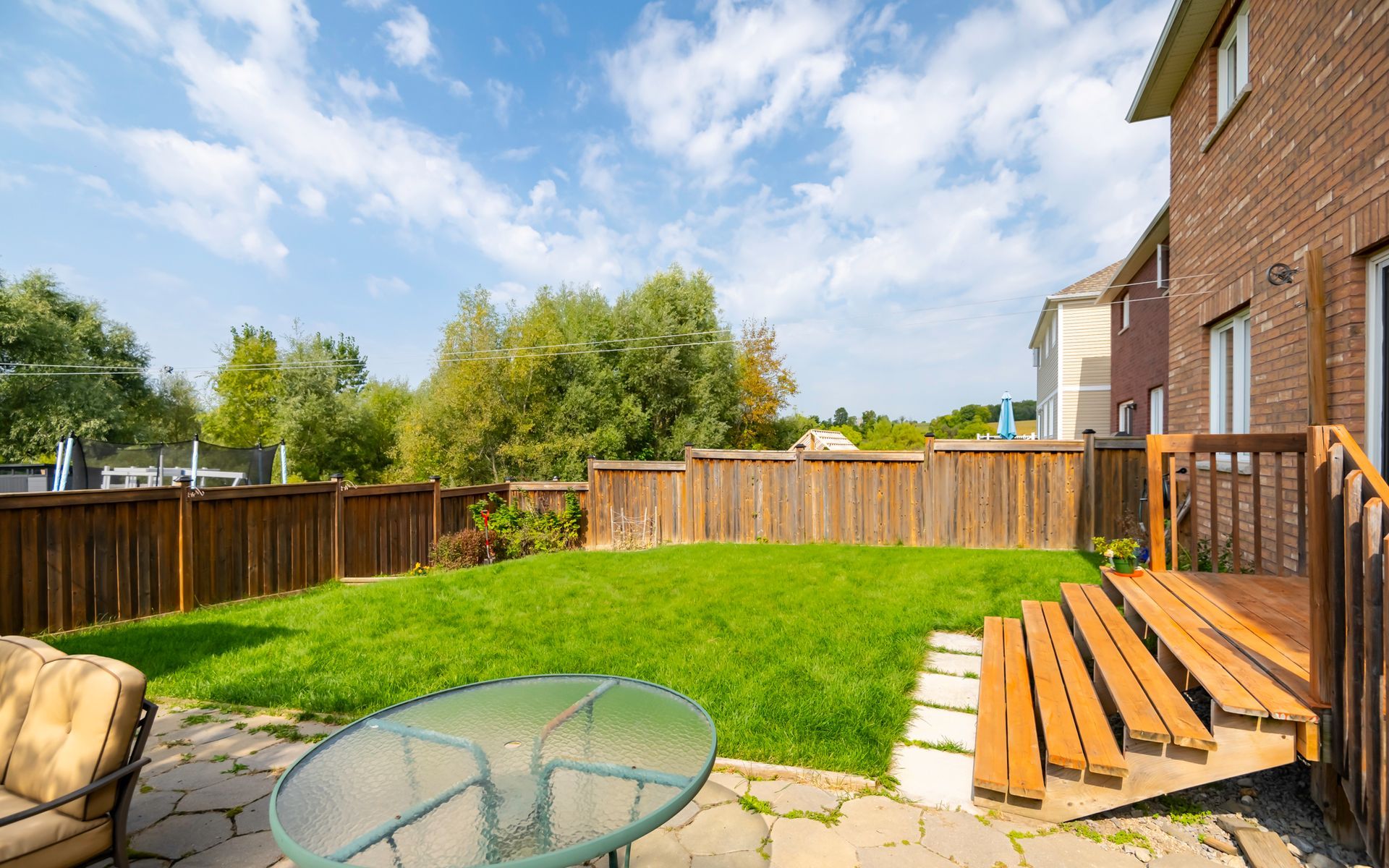 A backyard with a table and chairs and a wooden deck.