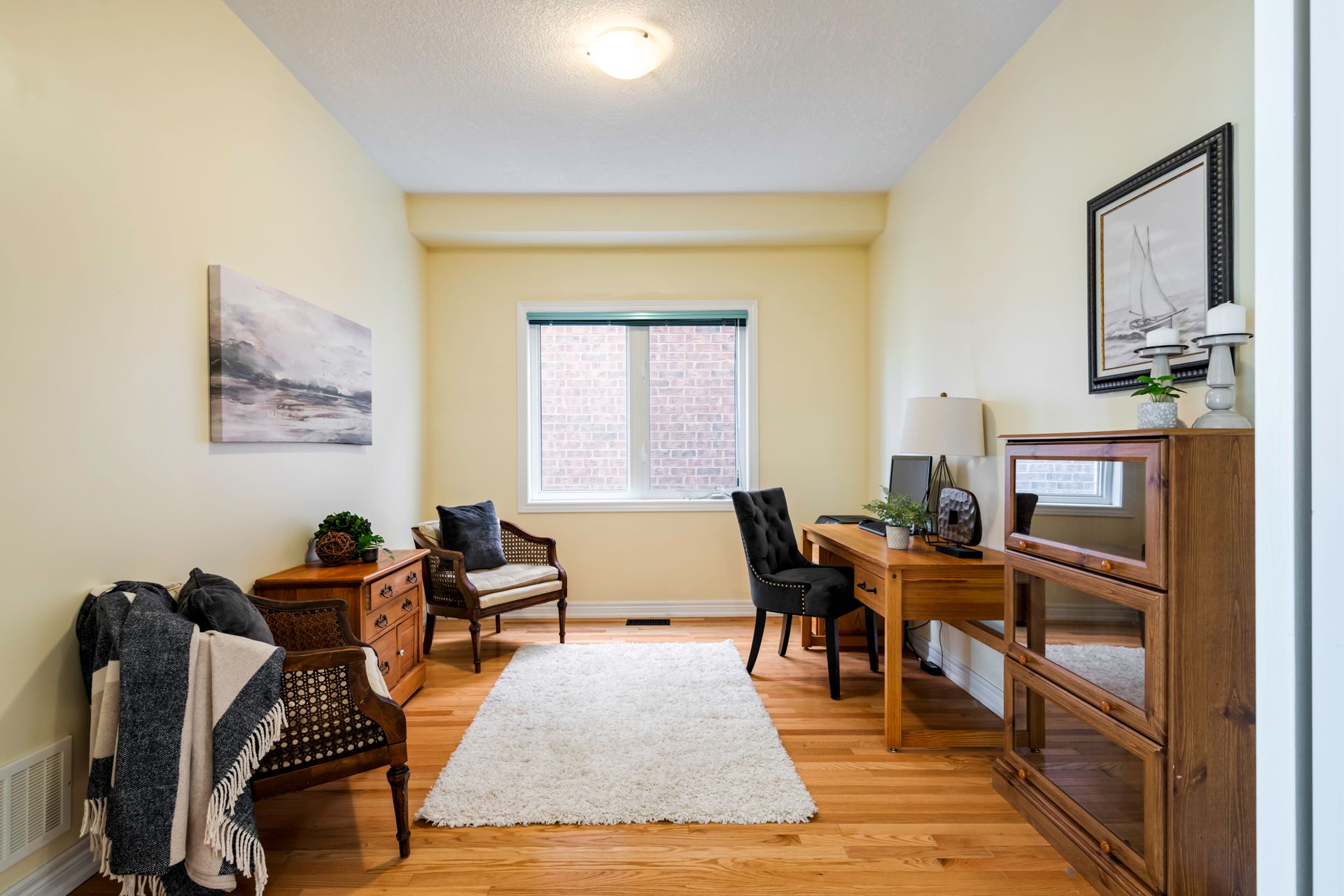 A living room with hardwood floors , a desk , chairs and a rug.