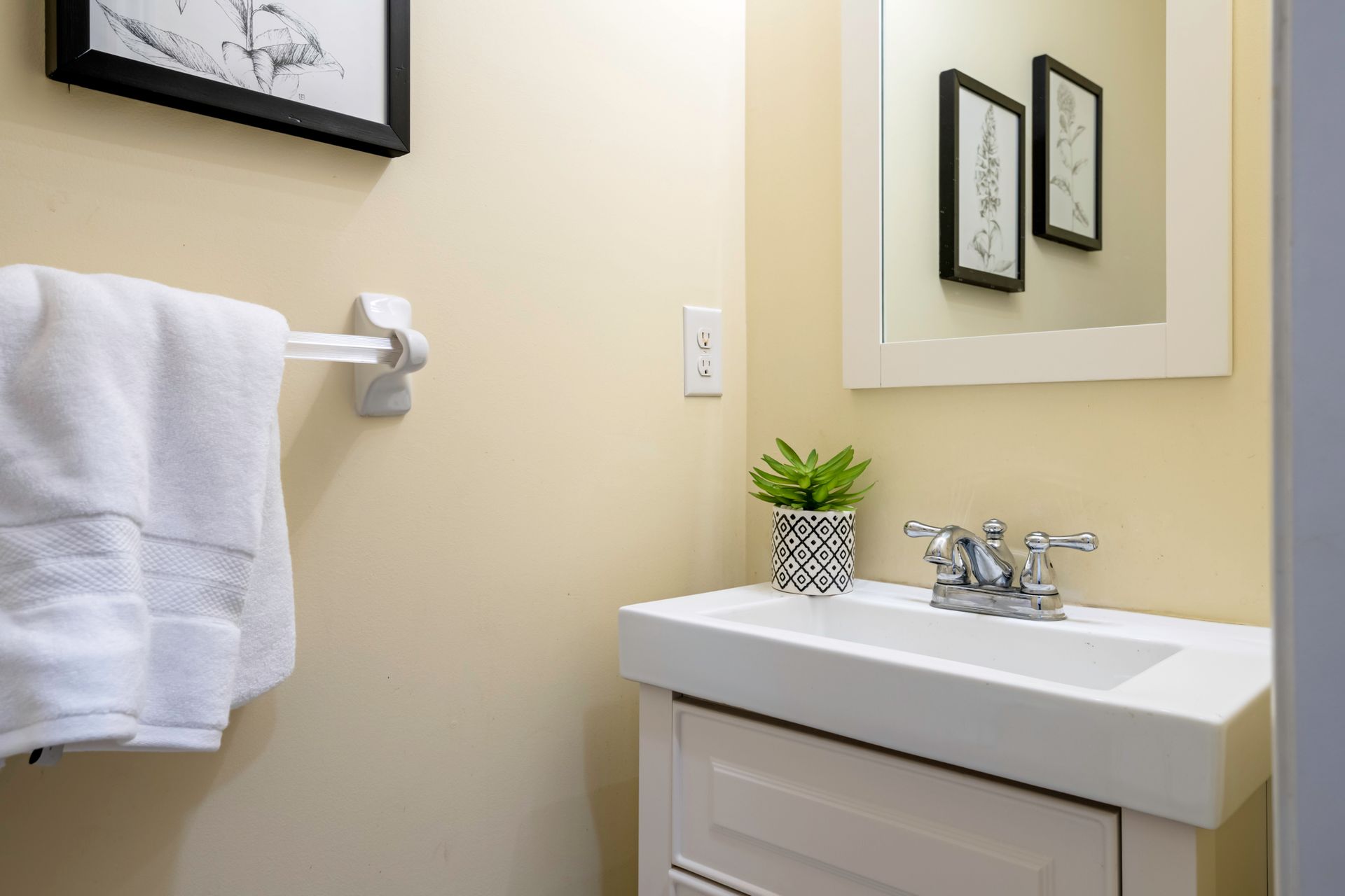 A bathroom with a sink , mirror and towel rack.