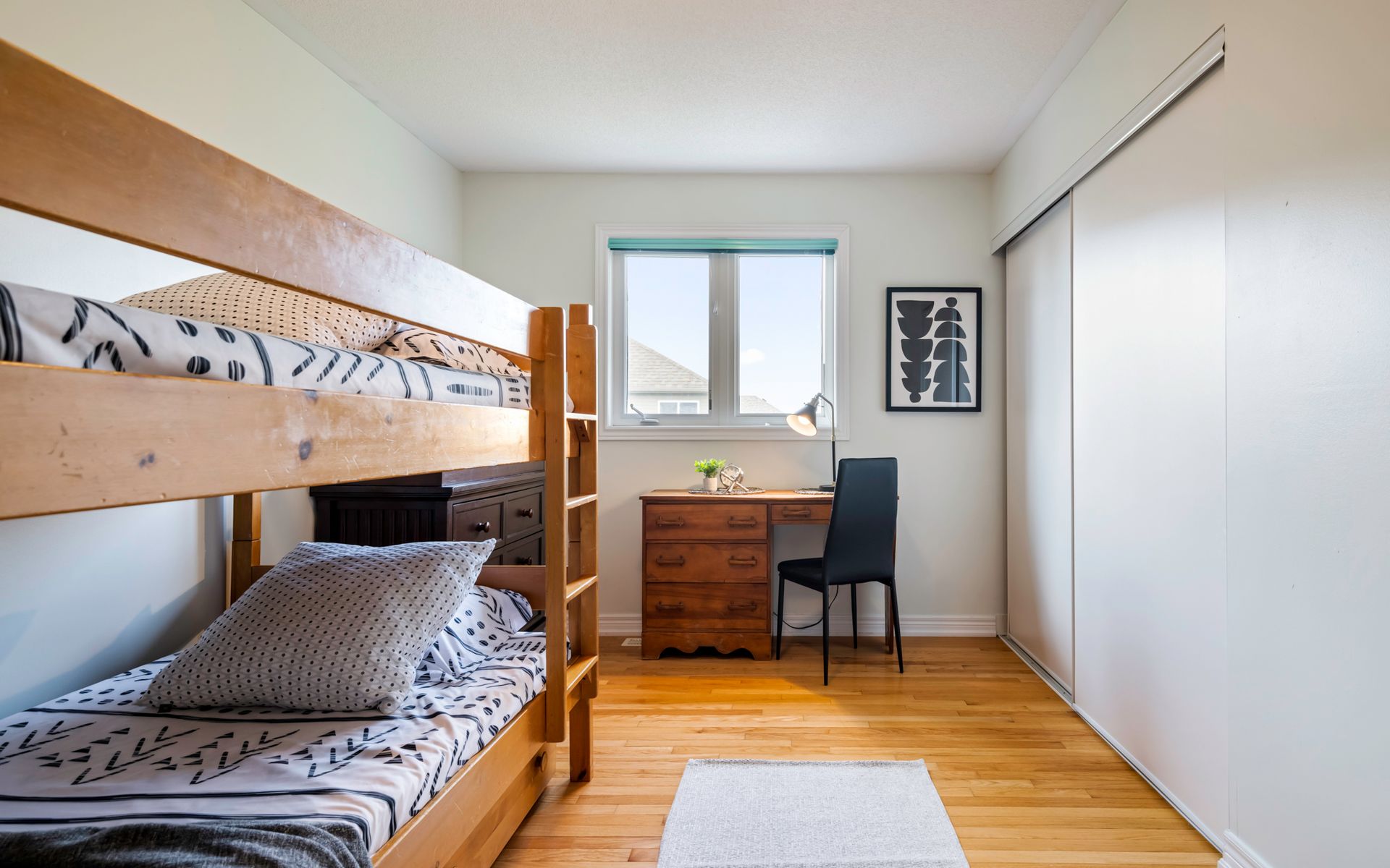 A bedroom with bunk beds , a desk , and a window.