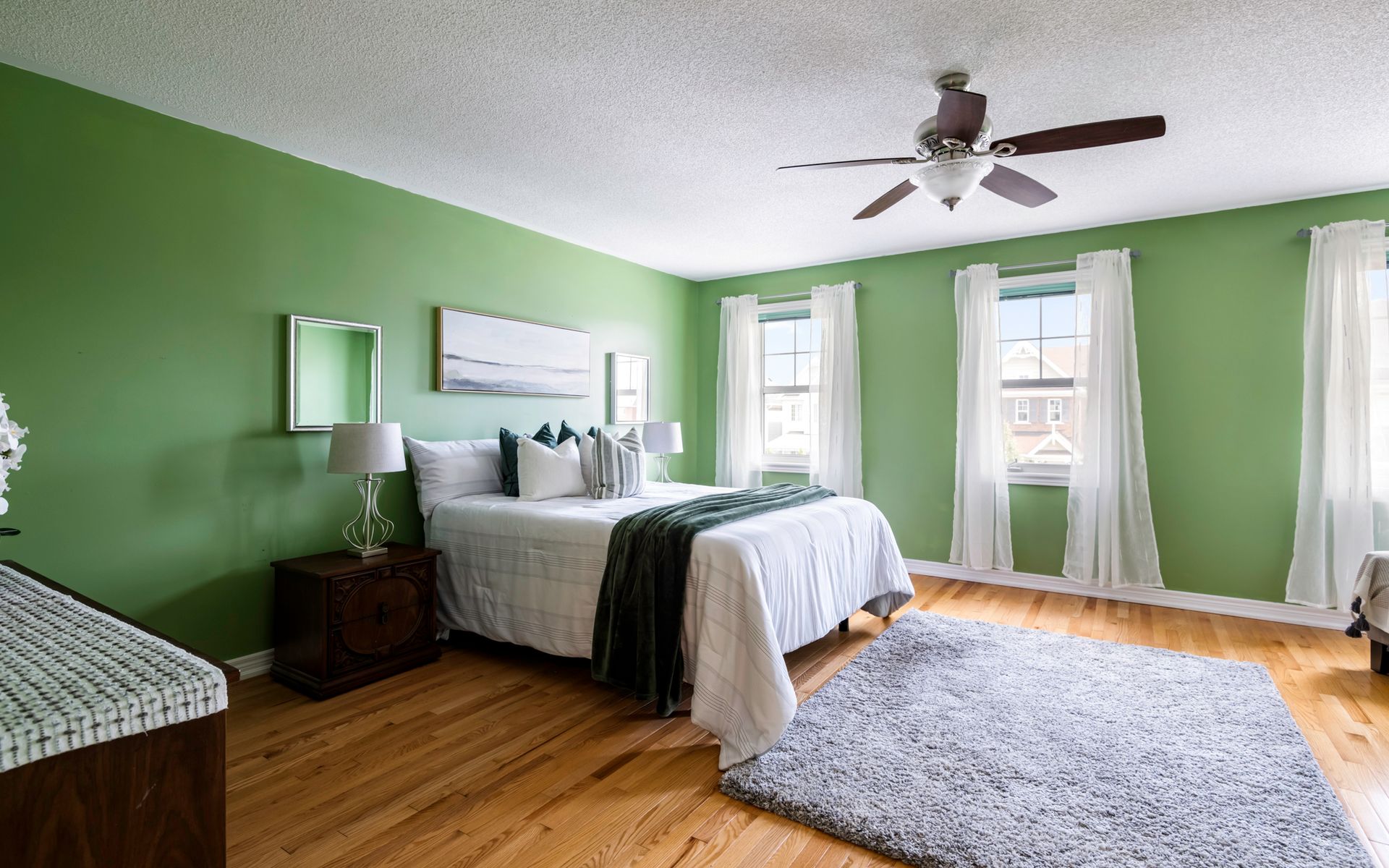 A bedroom with green walls and a ceiling fan.