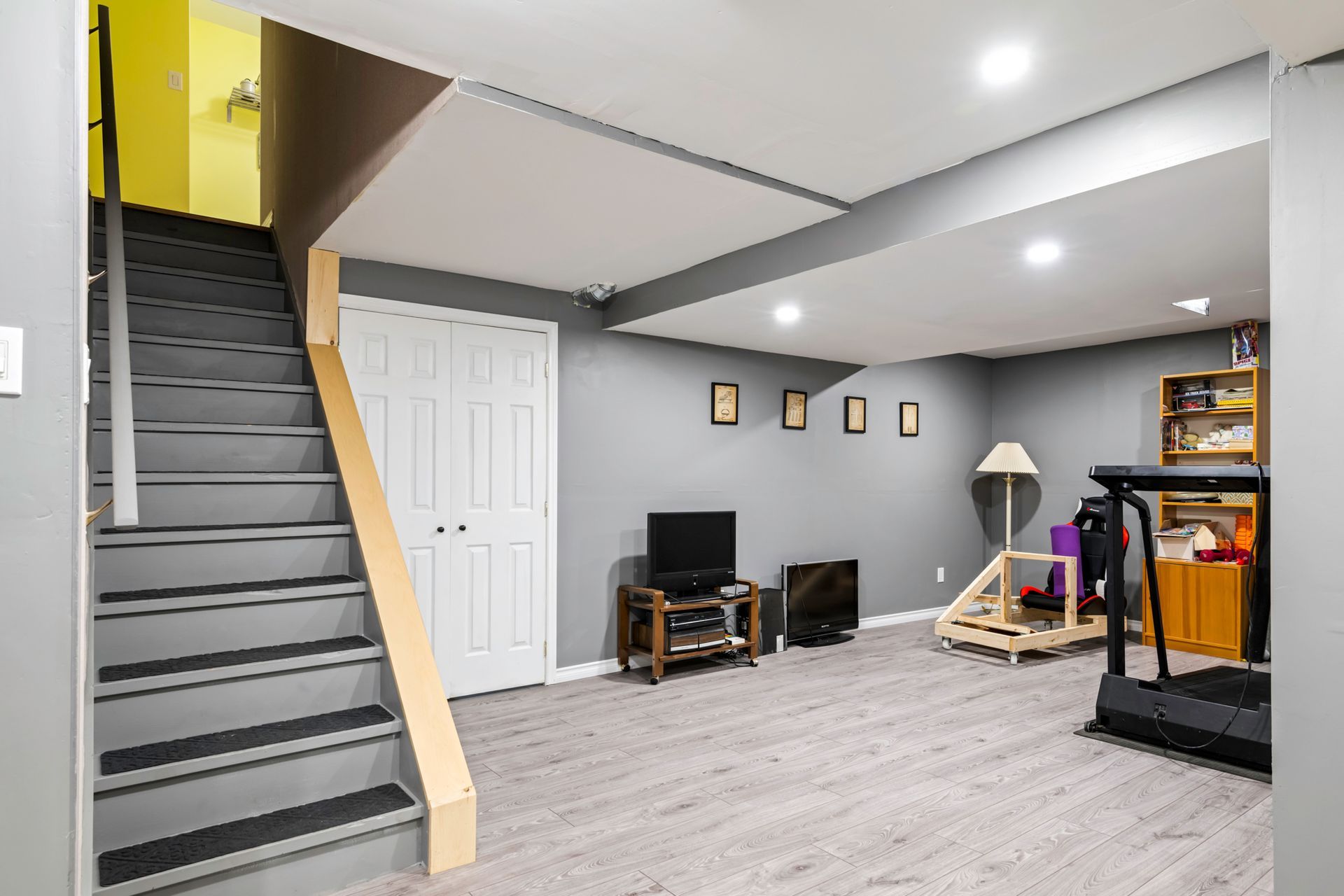 A basement with stairs leading up to the second floor and a treadmill.