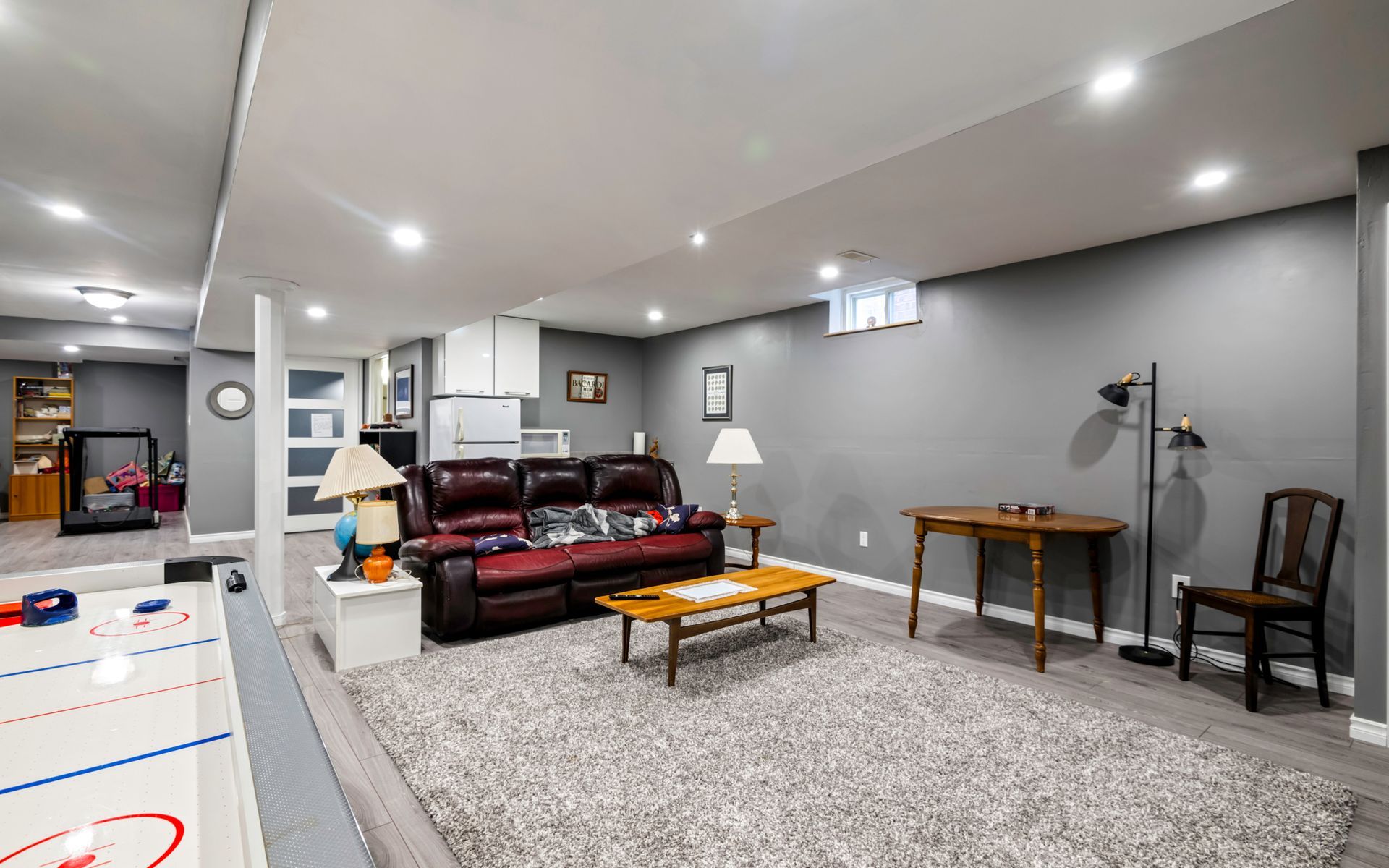 A living room in a basement with a couch , table and chairs.