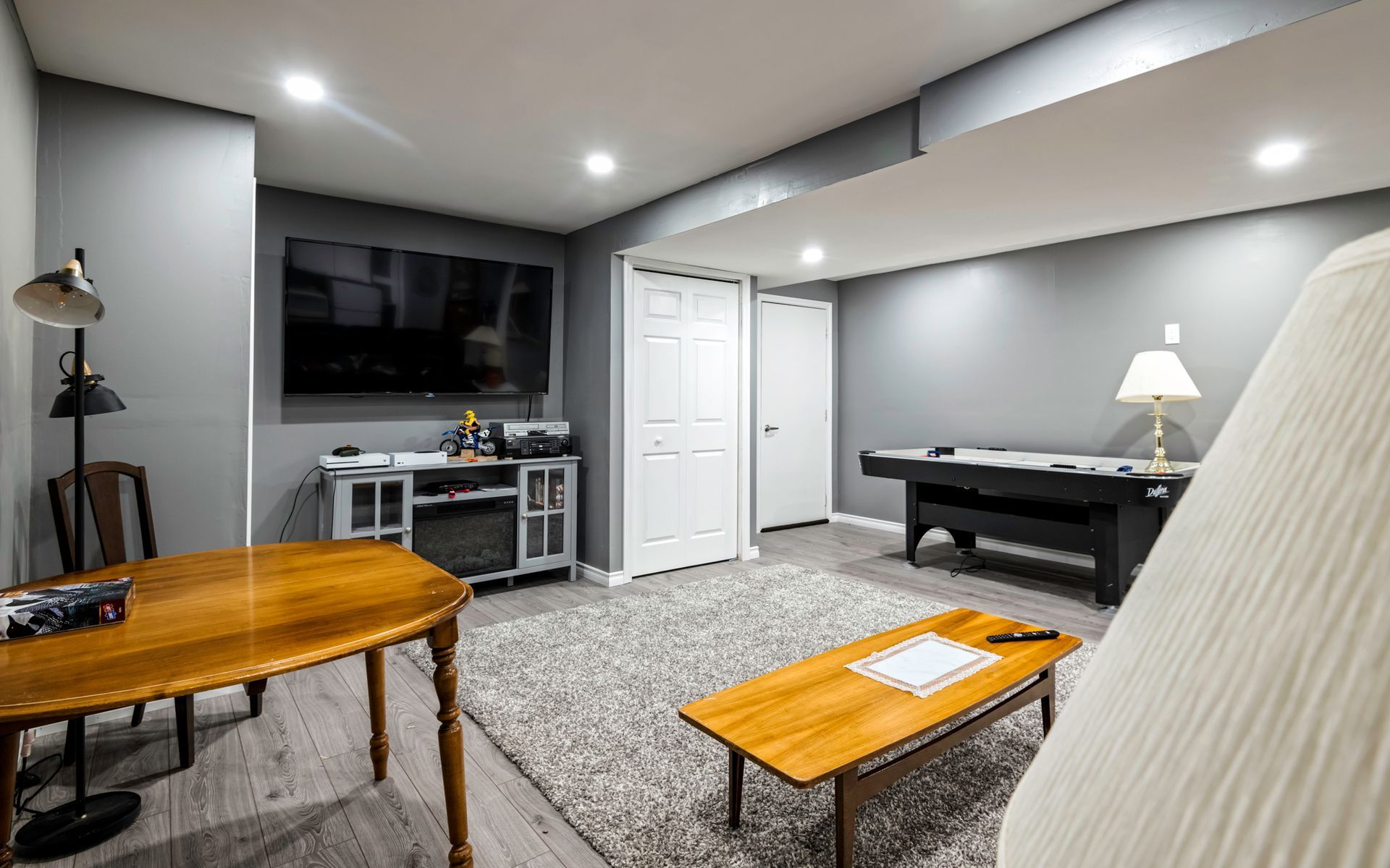 A living room with a pool table and a flat screen tv.