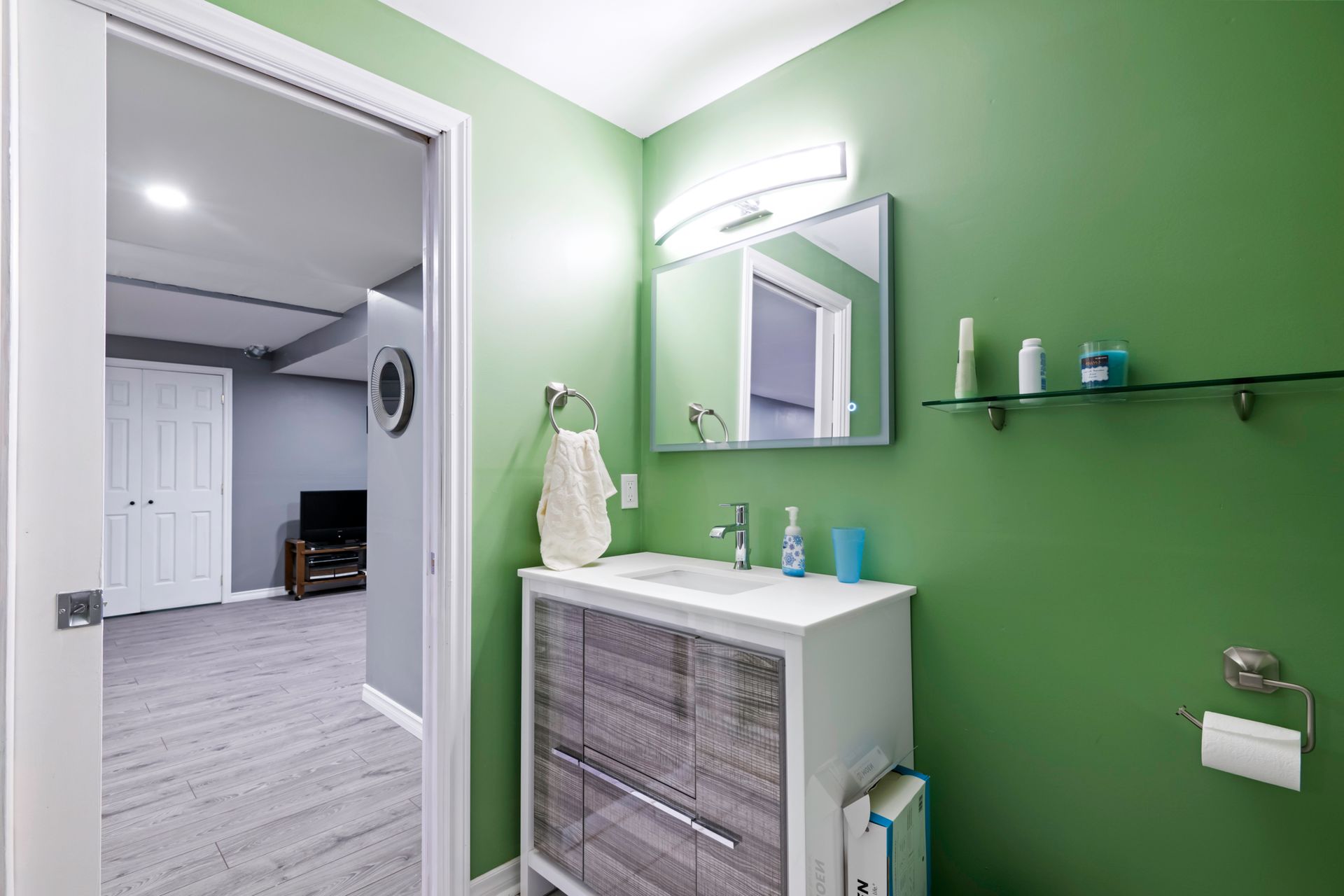 A bathroom with green walls , a sink and a mirror.
