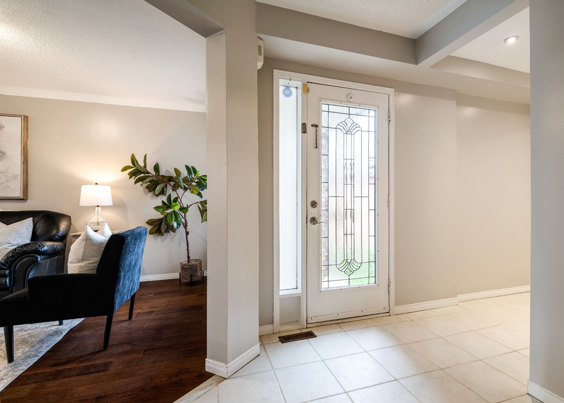 A living room with a couch , chair , lamp and a door.