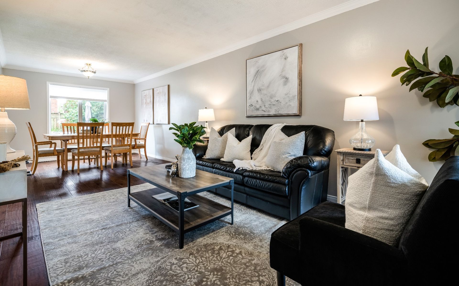 A living room with a couch , chair , coffee table and dining table.