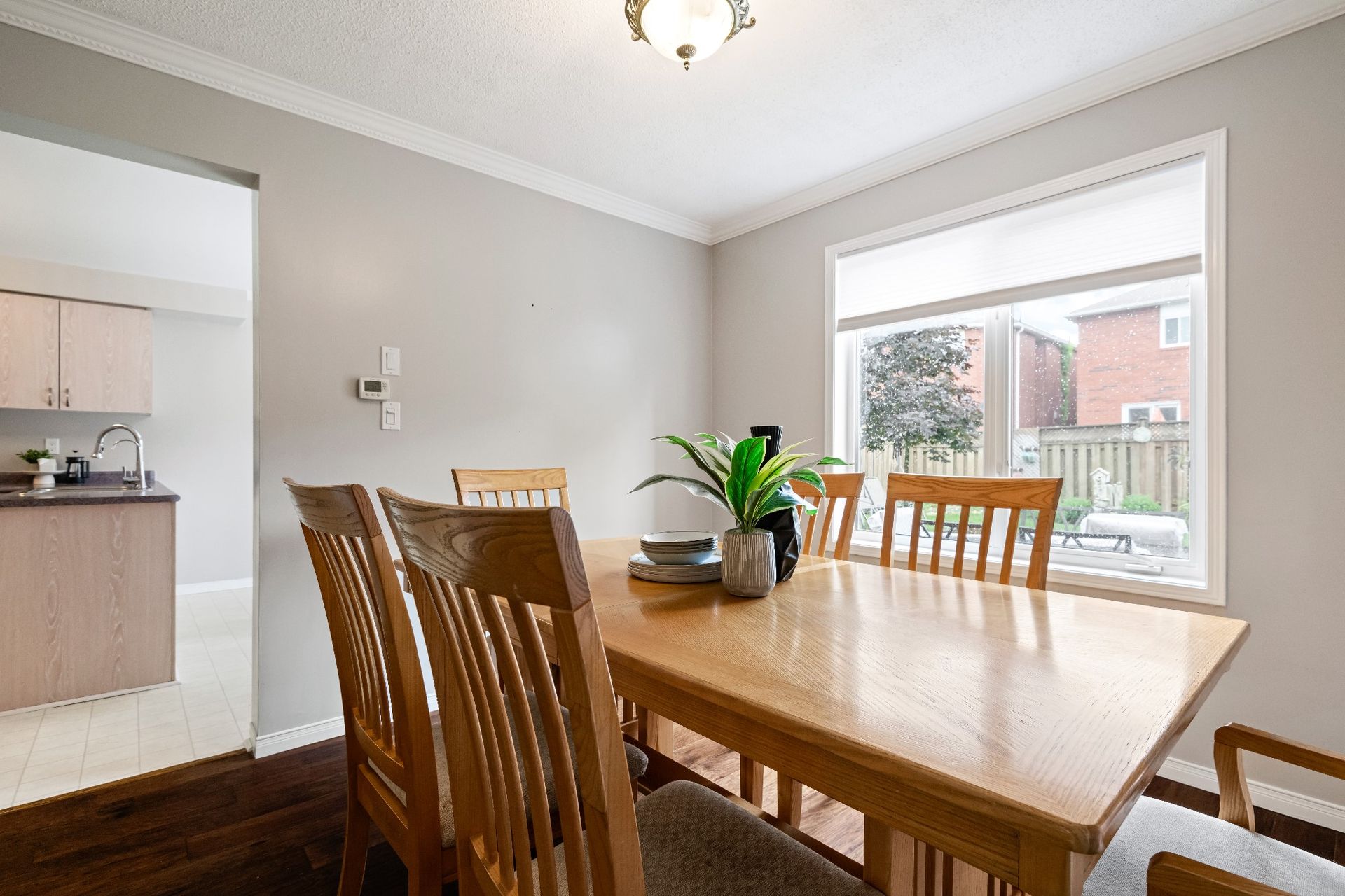 A dining room with a wooden table and chairs and a large window.
