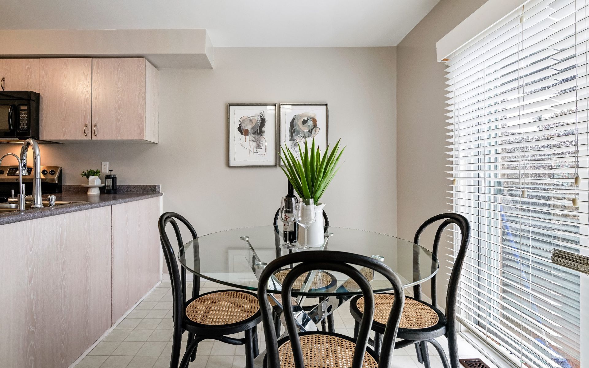 A dining room with a glass table and chairs in front of a window.