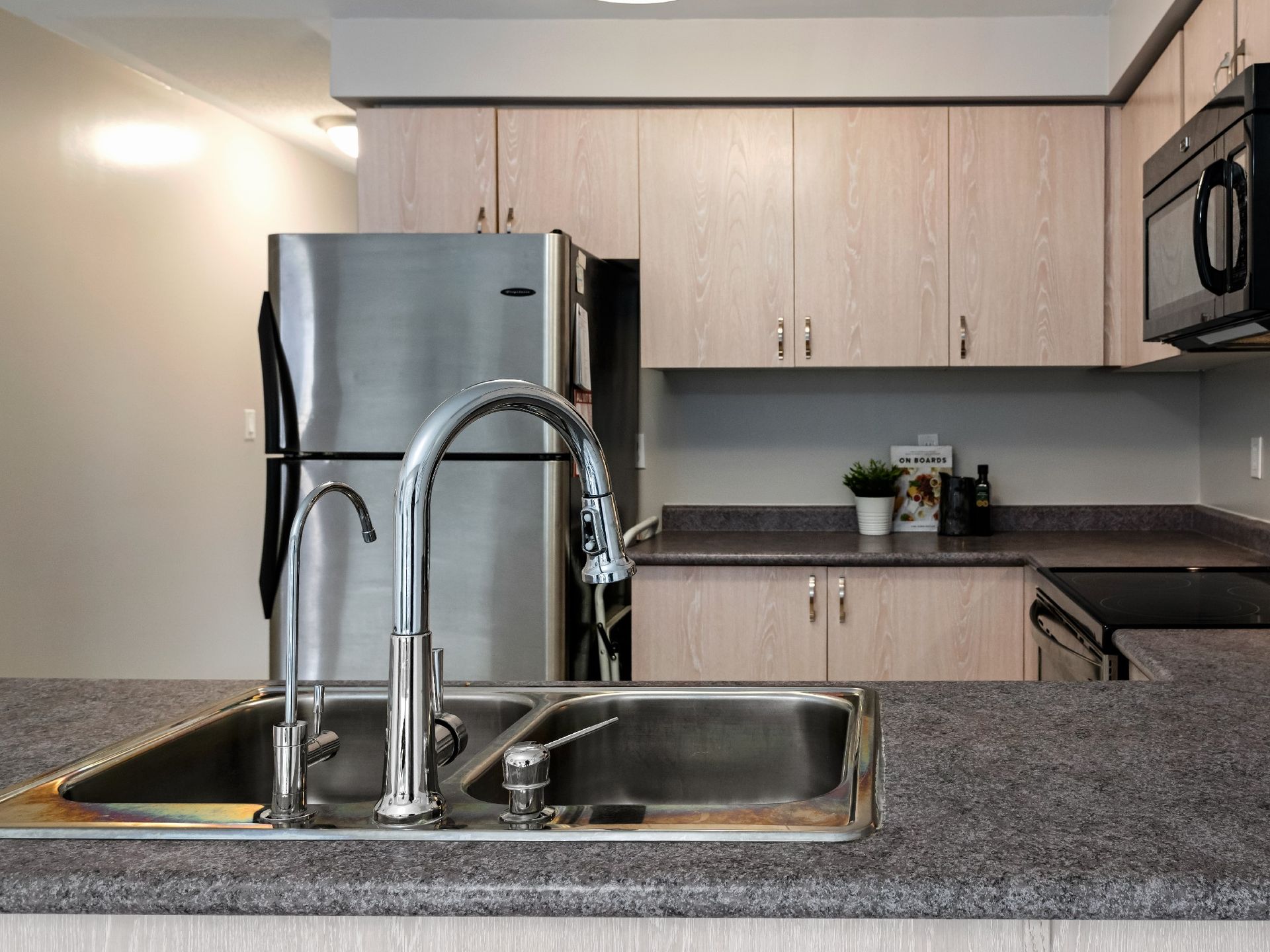 A kitchen with a sink a refrigerator and a microwave