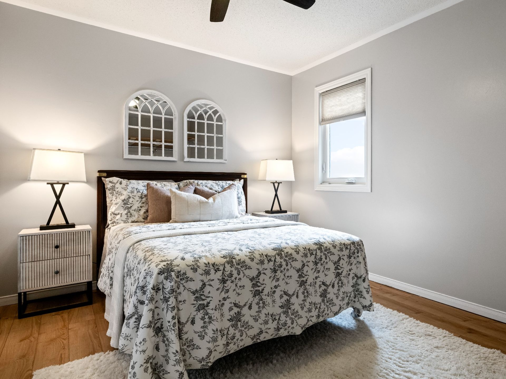 A bedroom with a bed , nightstands , lamps and a window.