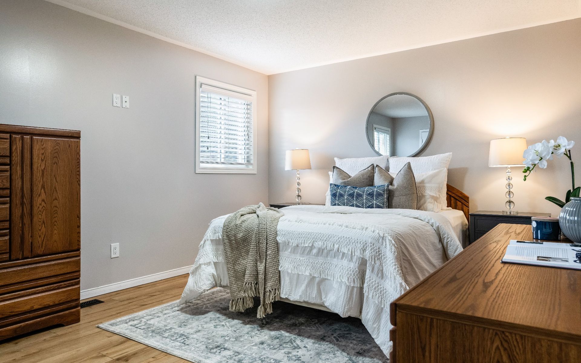 A bedroom with a bed , dresser , nightstand and mirror.