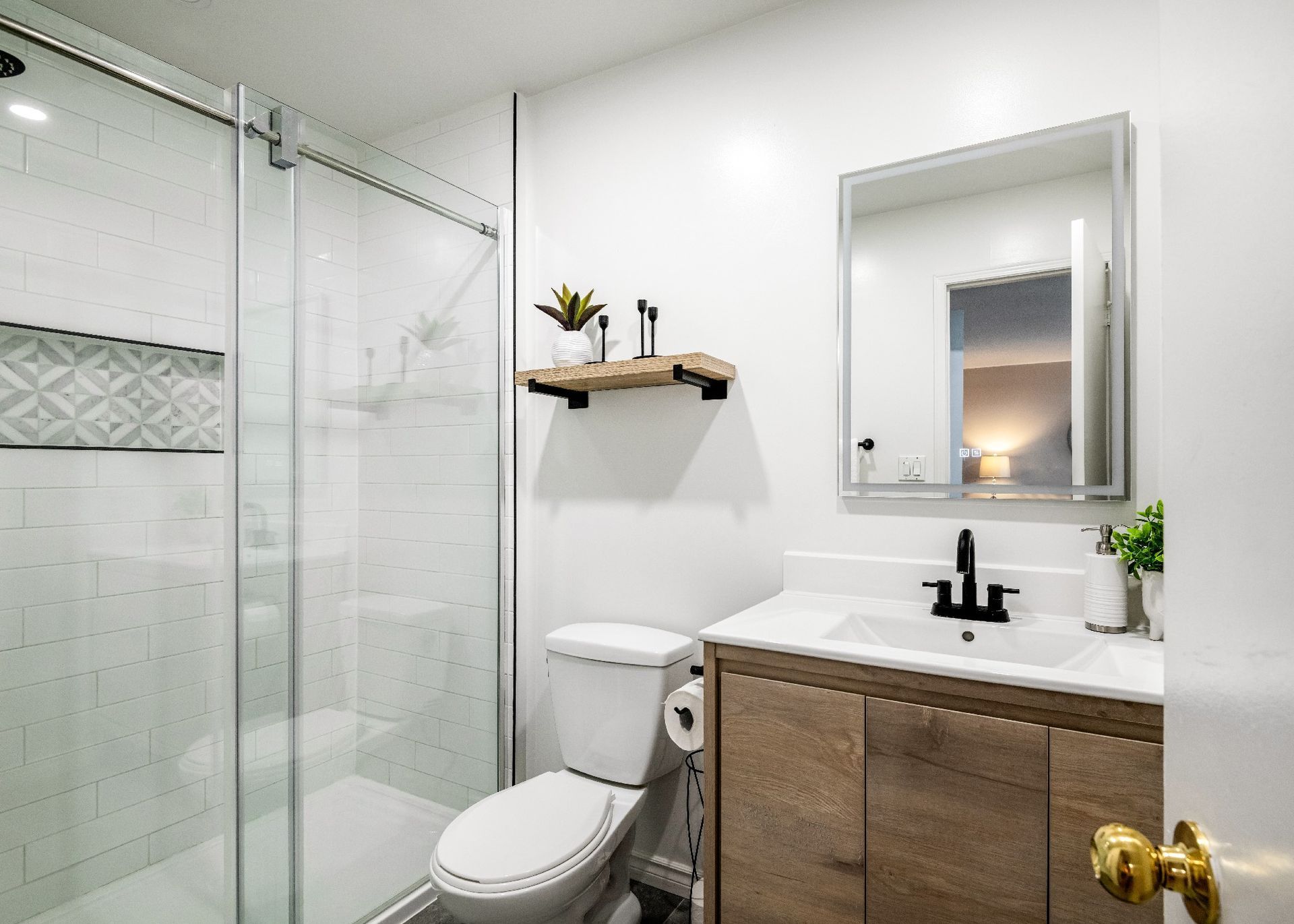 A bathroom with a toilet , sink , mirror and shower.