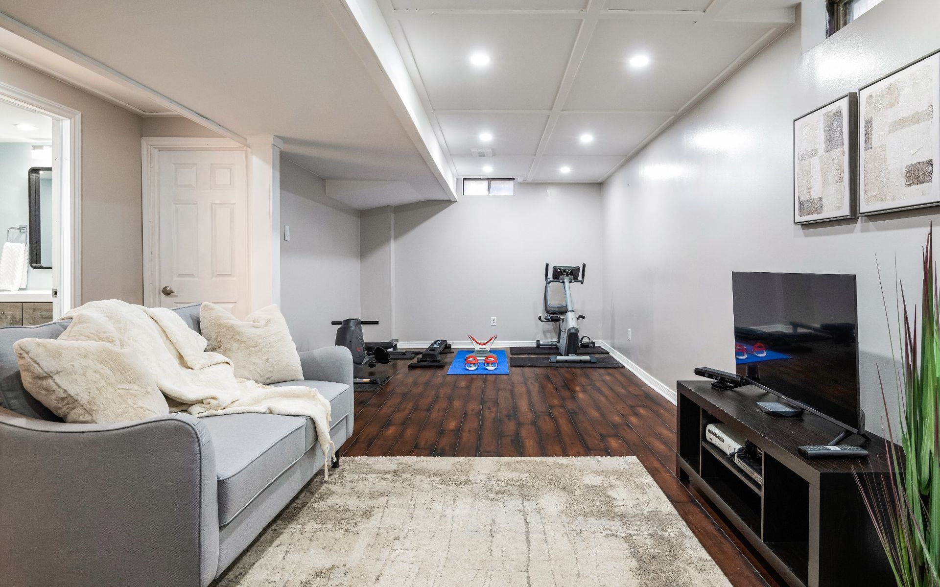 A living room with a couch and a television in a basement.