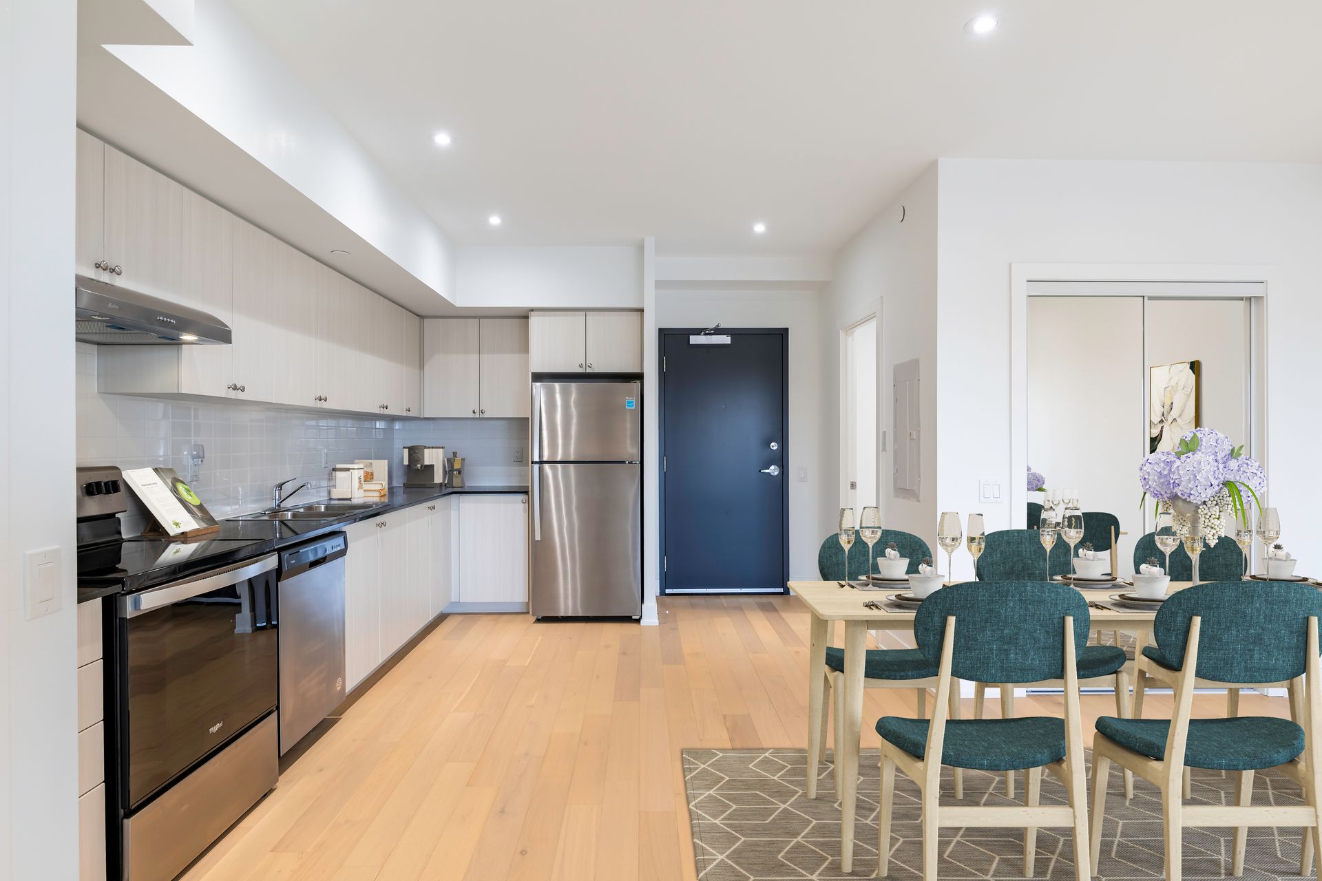 a kitchen with stainless steel appliances and a dining room with a table and chairs .