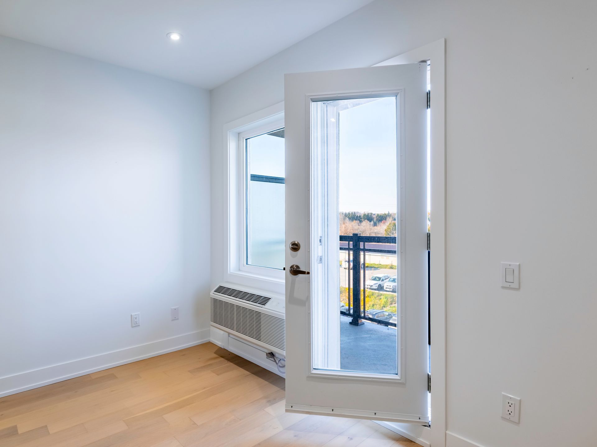 An empty room with a door open to a balcony.
