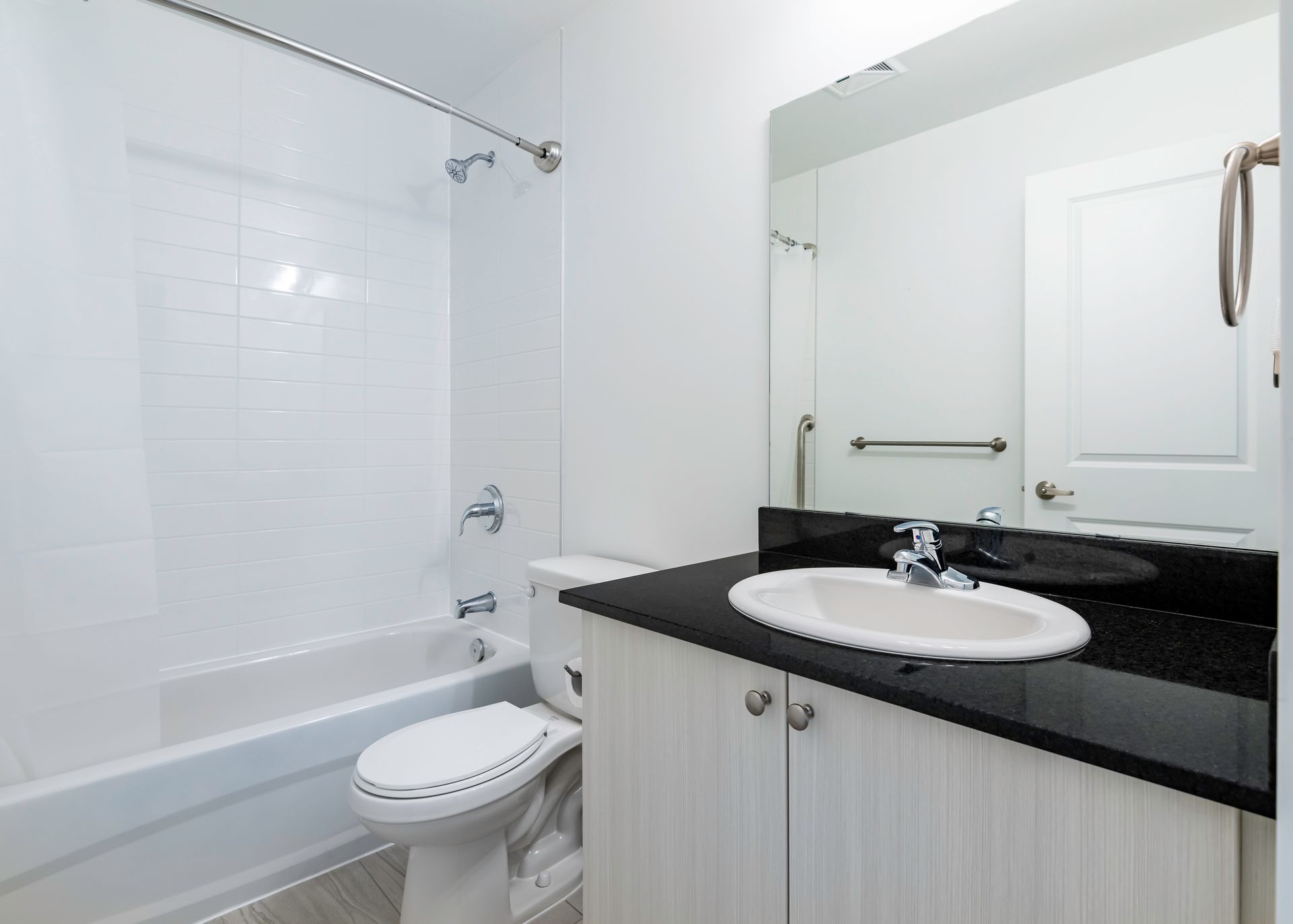 A bathroom with a toilet , sink , bathtub and mirror.