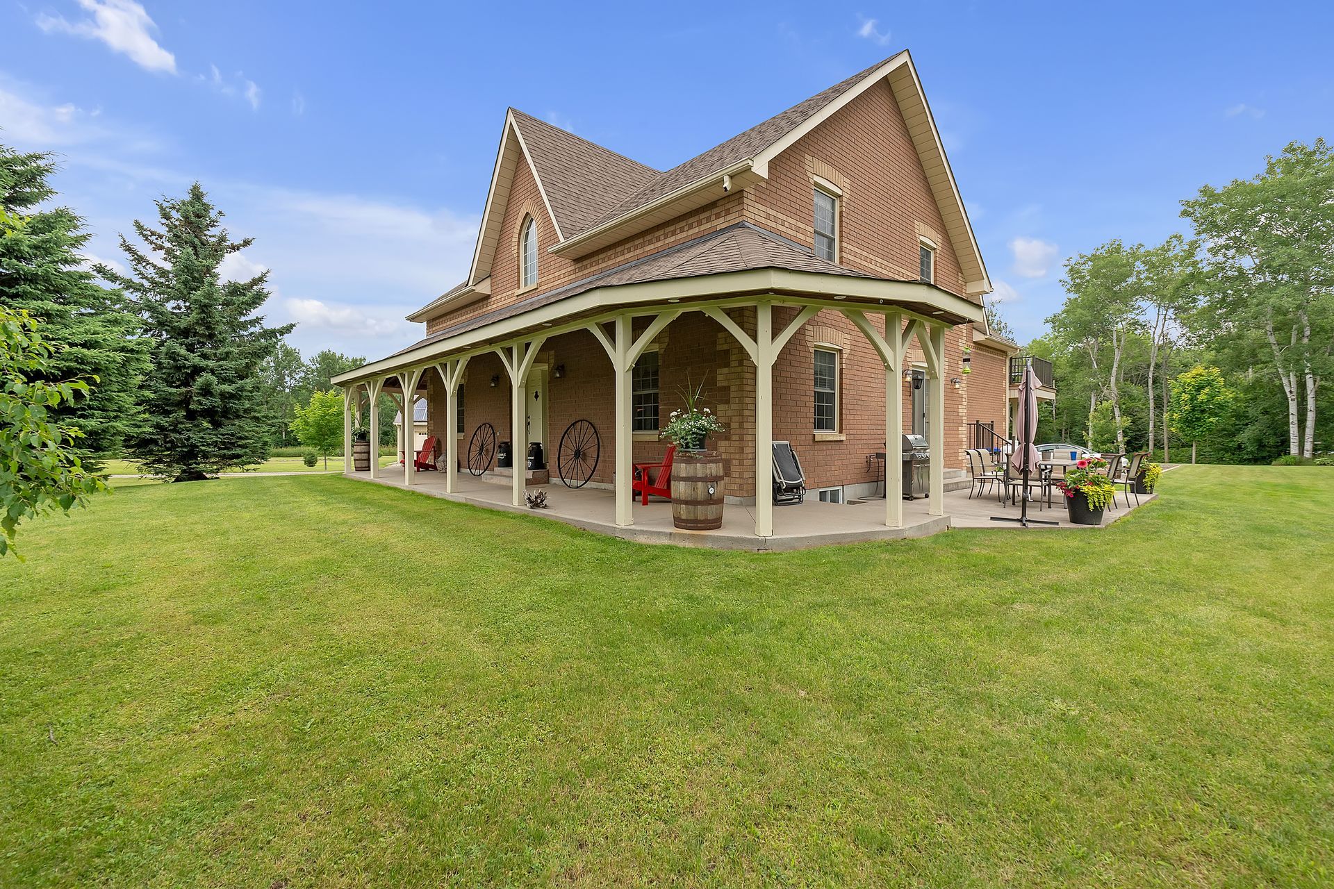 A large brick house with a porch and a large lawn in front of it.