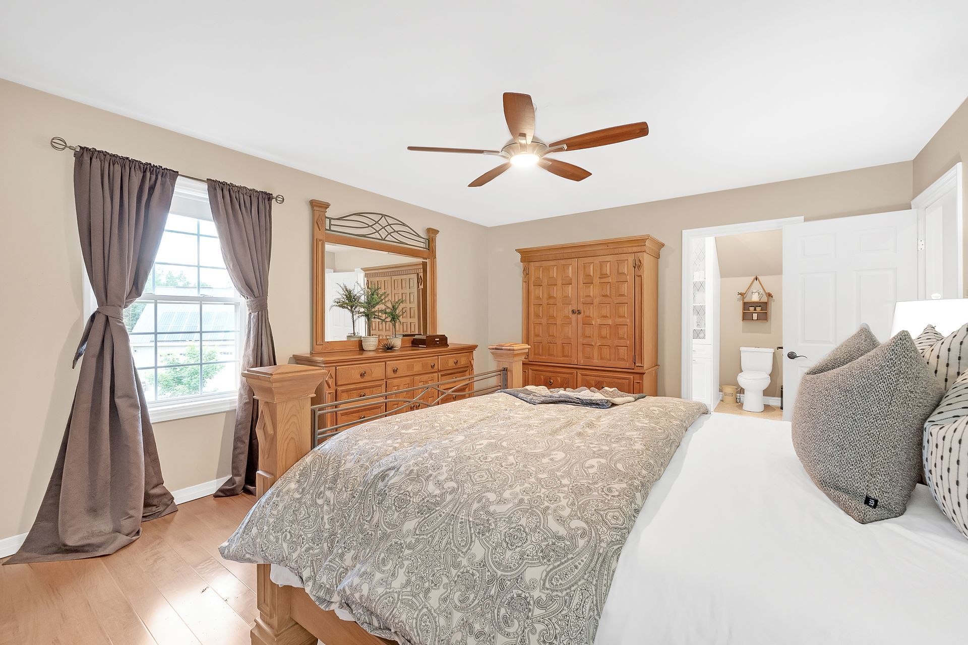 A bedroom with a bed , dresser , mirror and ceiling fan.
