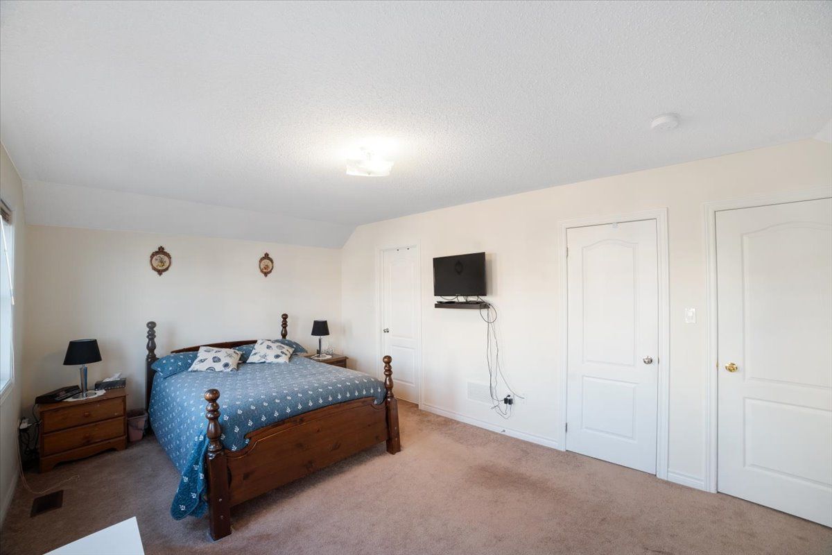 A bedroom with a large bed and a flat screen tv on the wall.