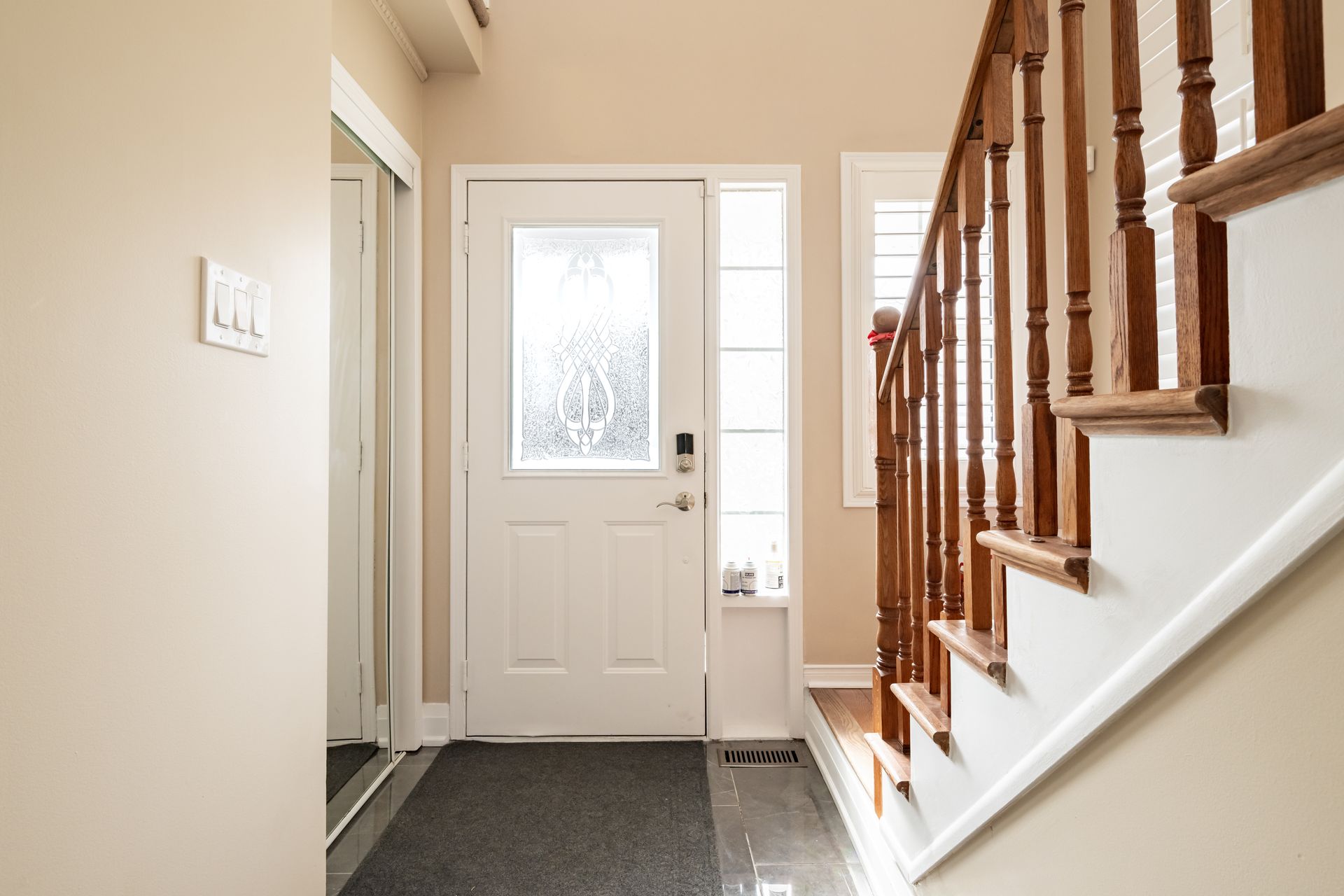 A hallway with stairs leading up to the front door of a house.