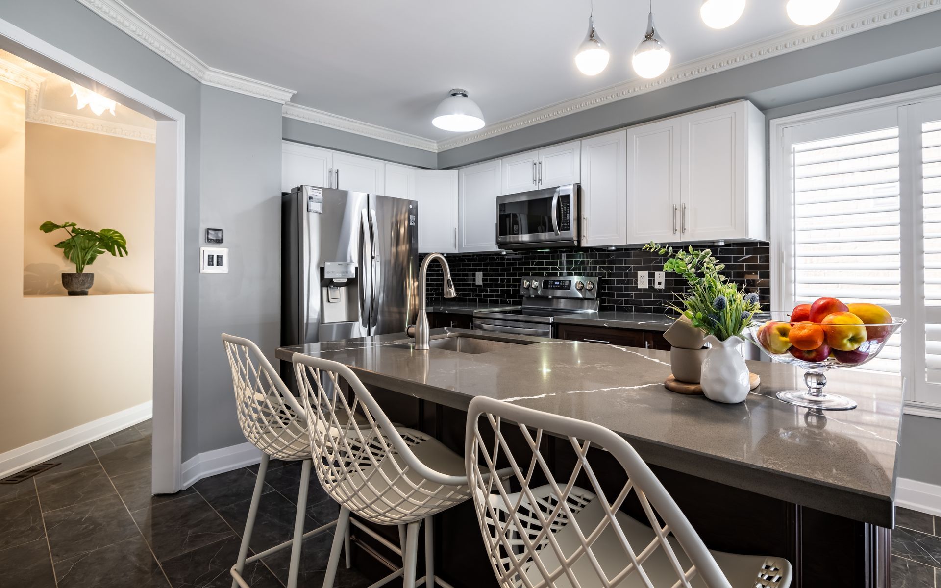 A kitchen with a large island and stools and a refrigerator.
