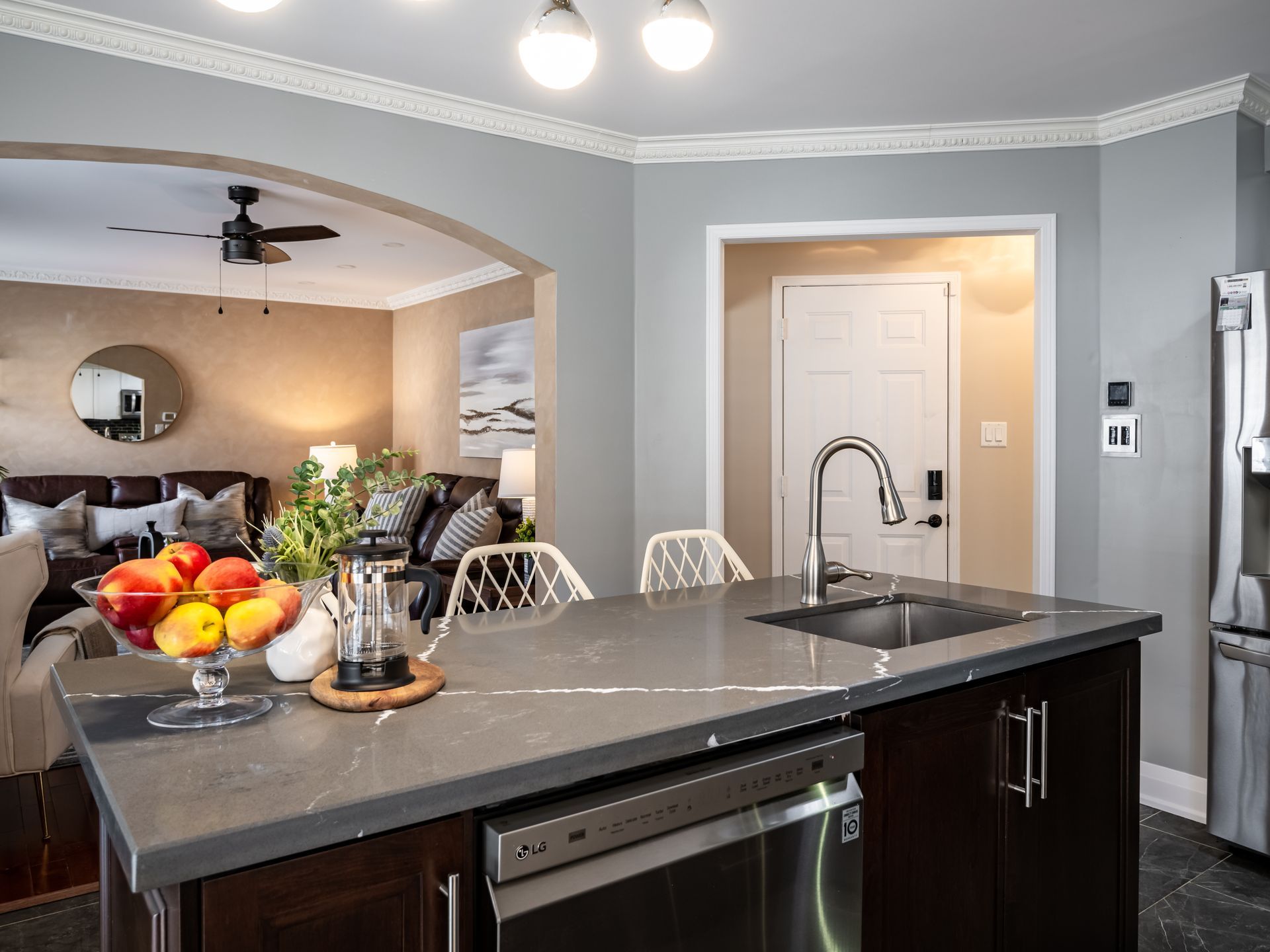 A kitchen with a large island , sink , dishwasher and refrigerator.