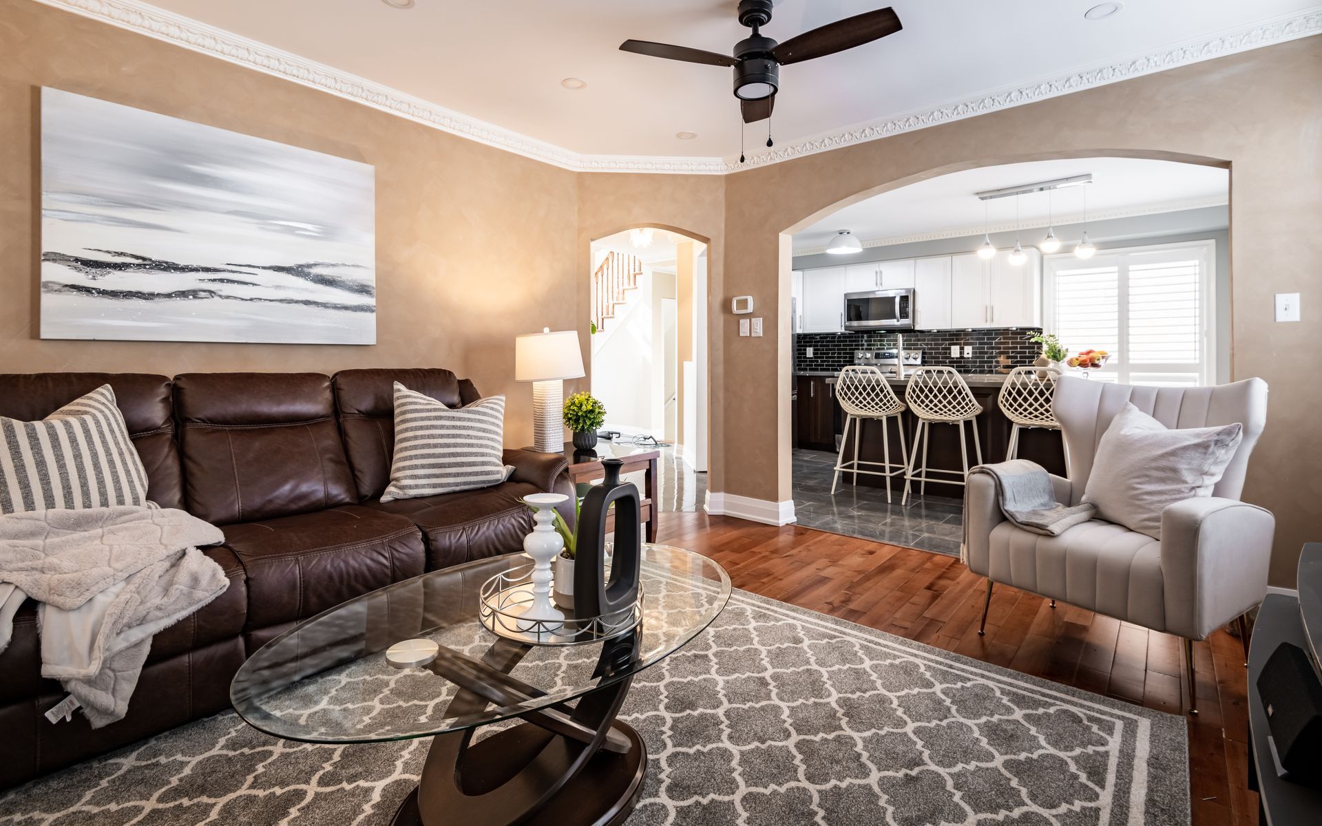 A living room with a couch , chair , coffee table and ceiling fan.
