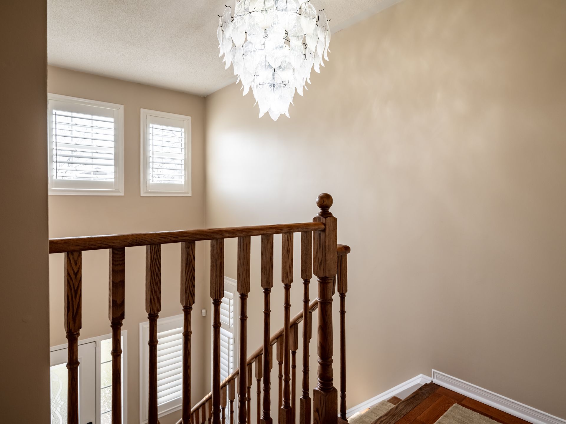 A staircase with a wooden railing and a chandelier hanging from the ceiling.