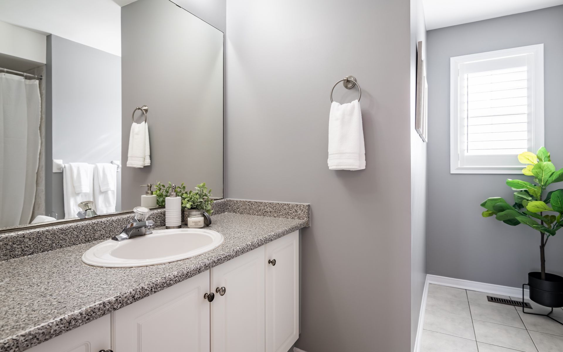 A bathroom with a sink , mirror and window.