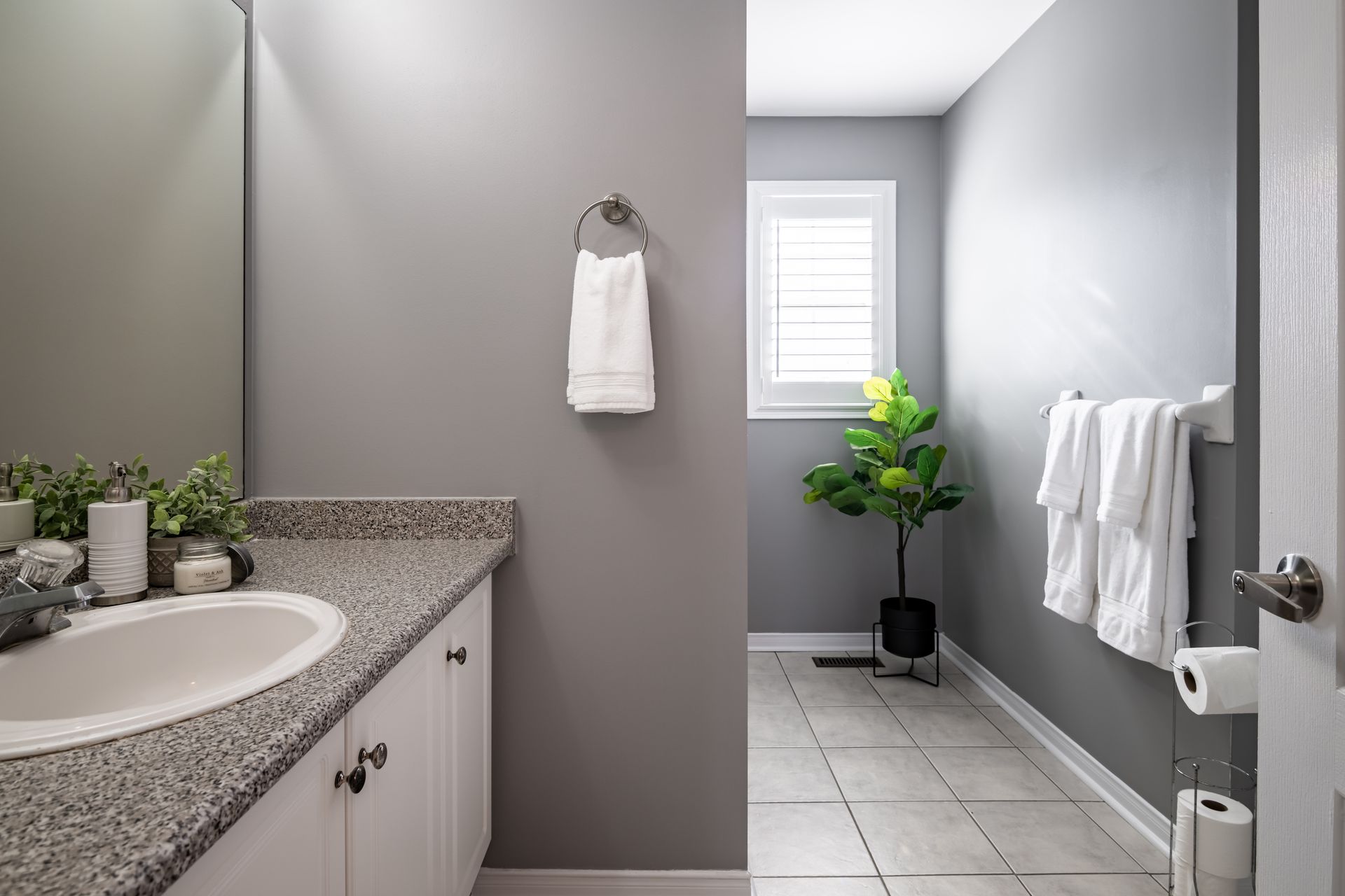 A bathroom with a sink , mirror , and towels hanging on the wall.