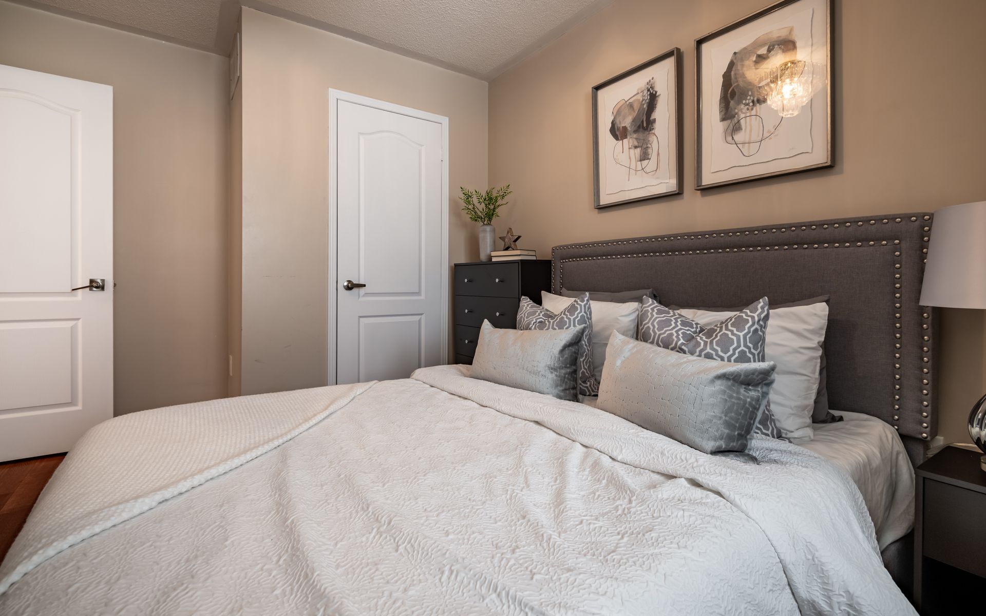 A bedroom with a large bed and two pictures on the wall.