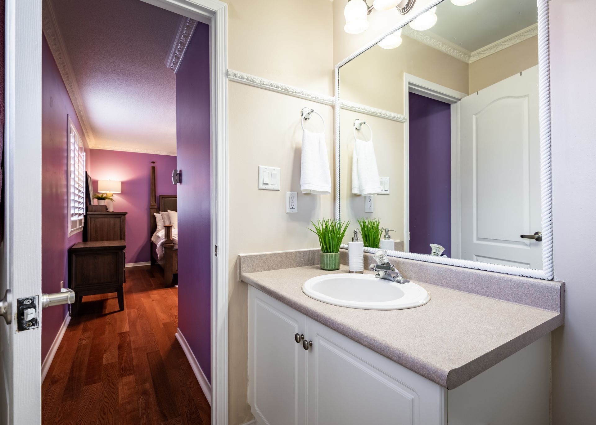 A bathroom with a sink , mirror and purple walls.