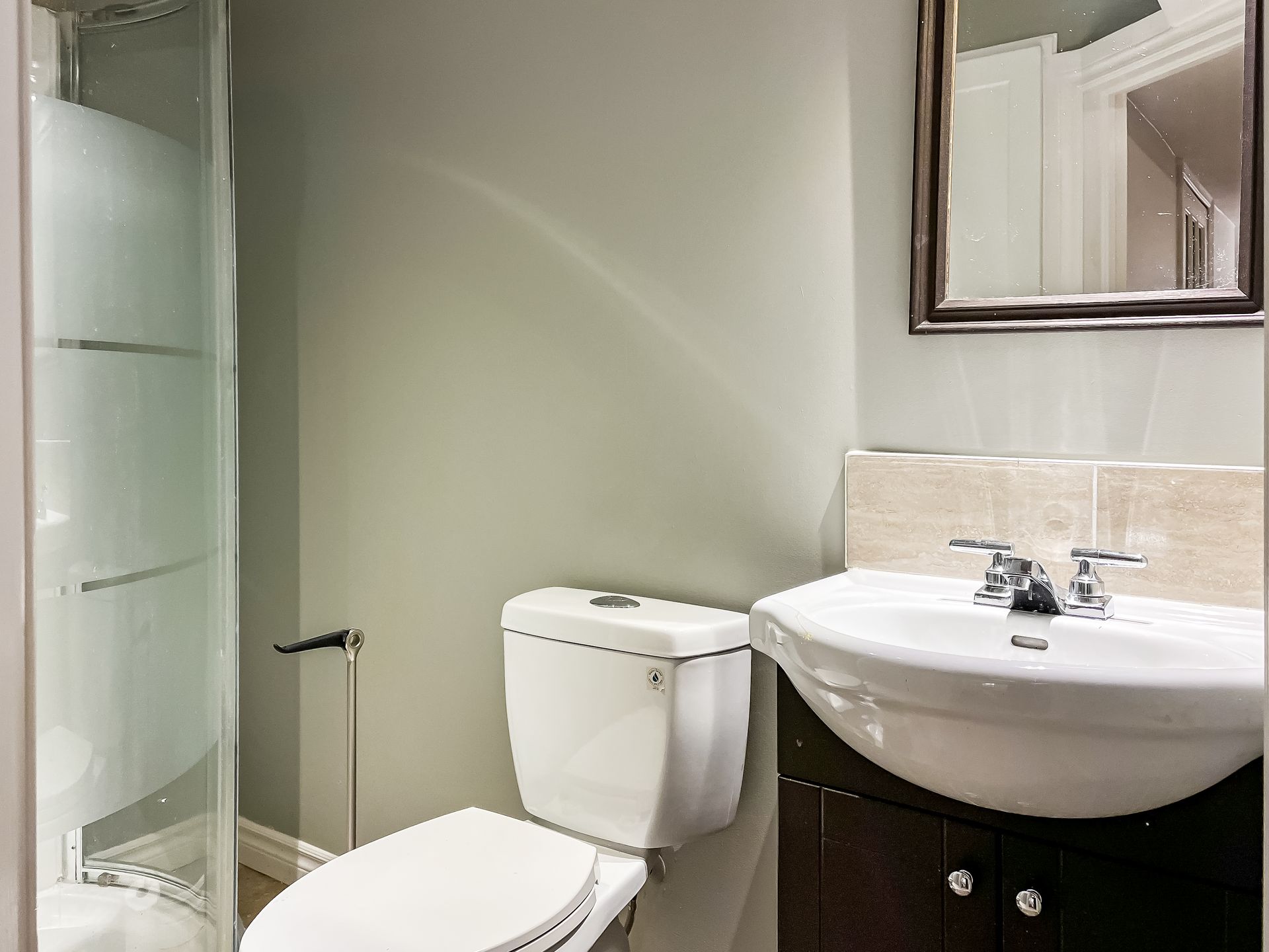 A bathroom with a toilet , sink and mirror.