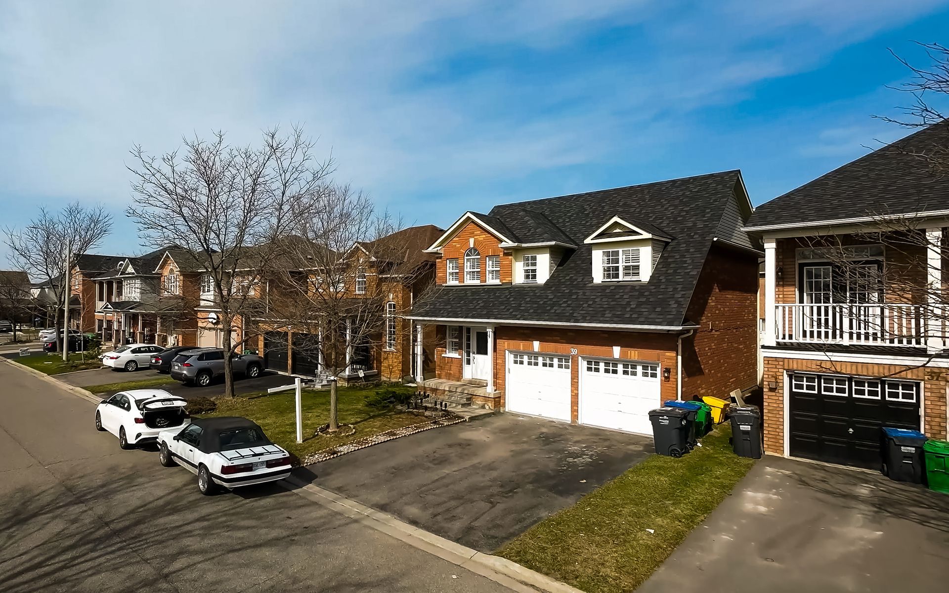 A row of houses in a residential area with cars parked in front of them.