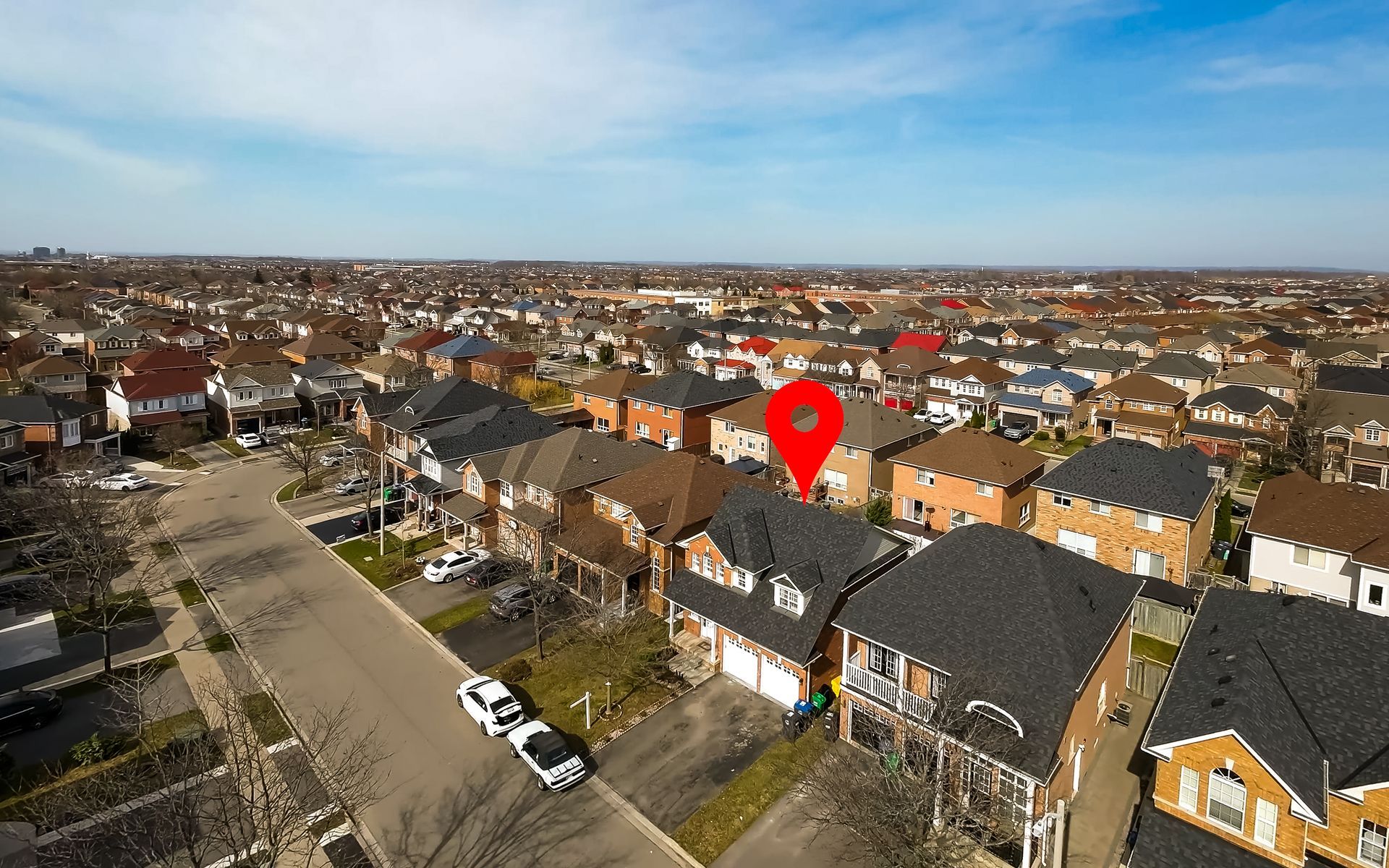 An aerial view of a residential area with a red pin pointing the location of a house.