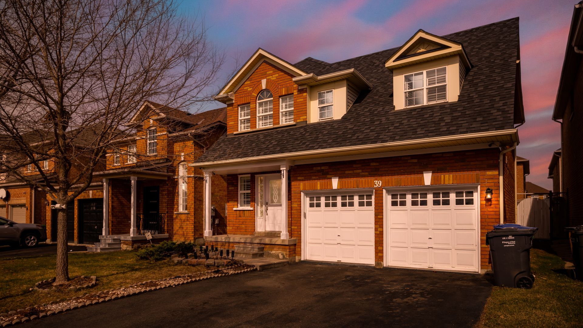 A large brick house with two garage doors and a car parked in front of it.