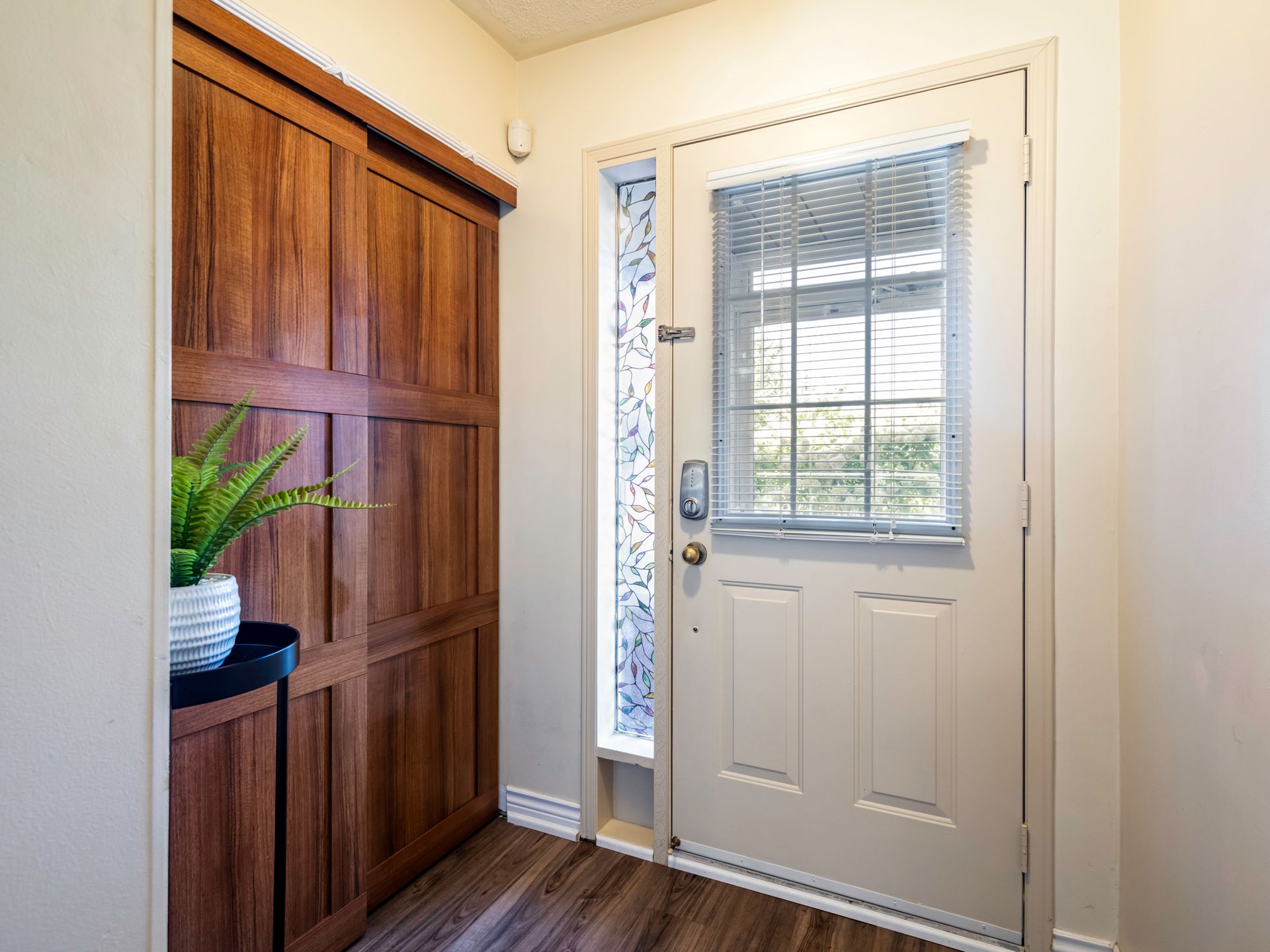 A hallway with a white door and wooden cabinets.
