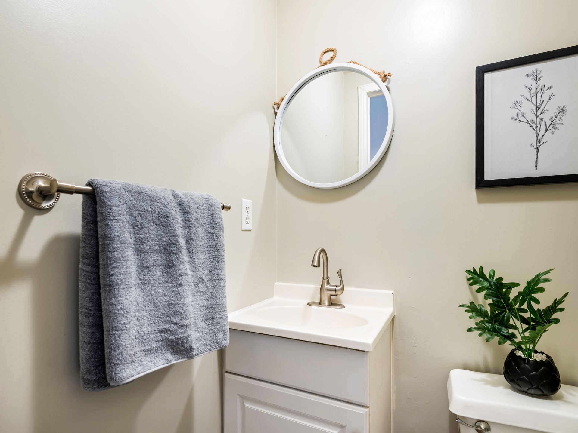 A bathroom with a sink , mirror , towel rack and toilet.