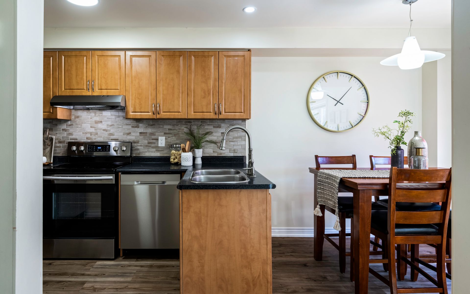 A kitchen with wooden cabinets and stainless steel appliances and a clock on the wall.
