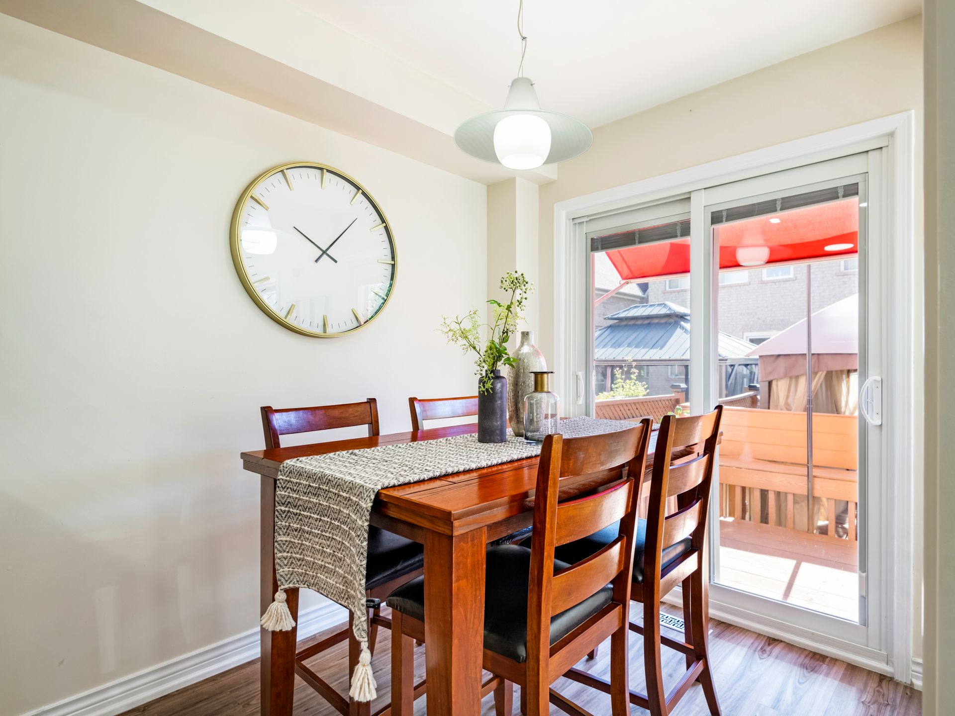 A dining room with a table and chairs and a clock on the wall.