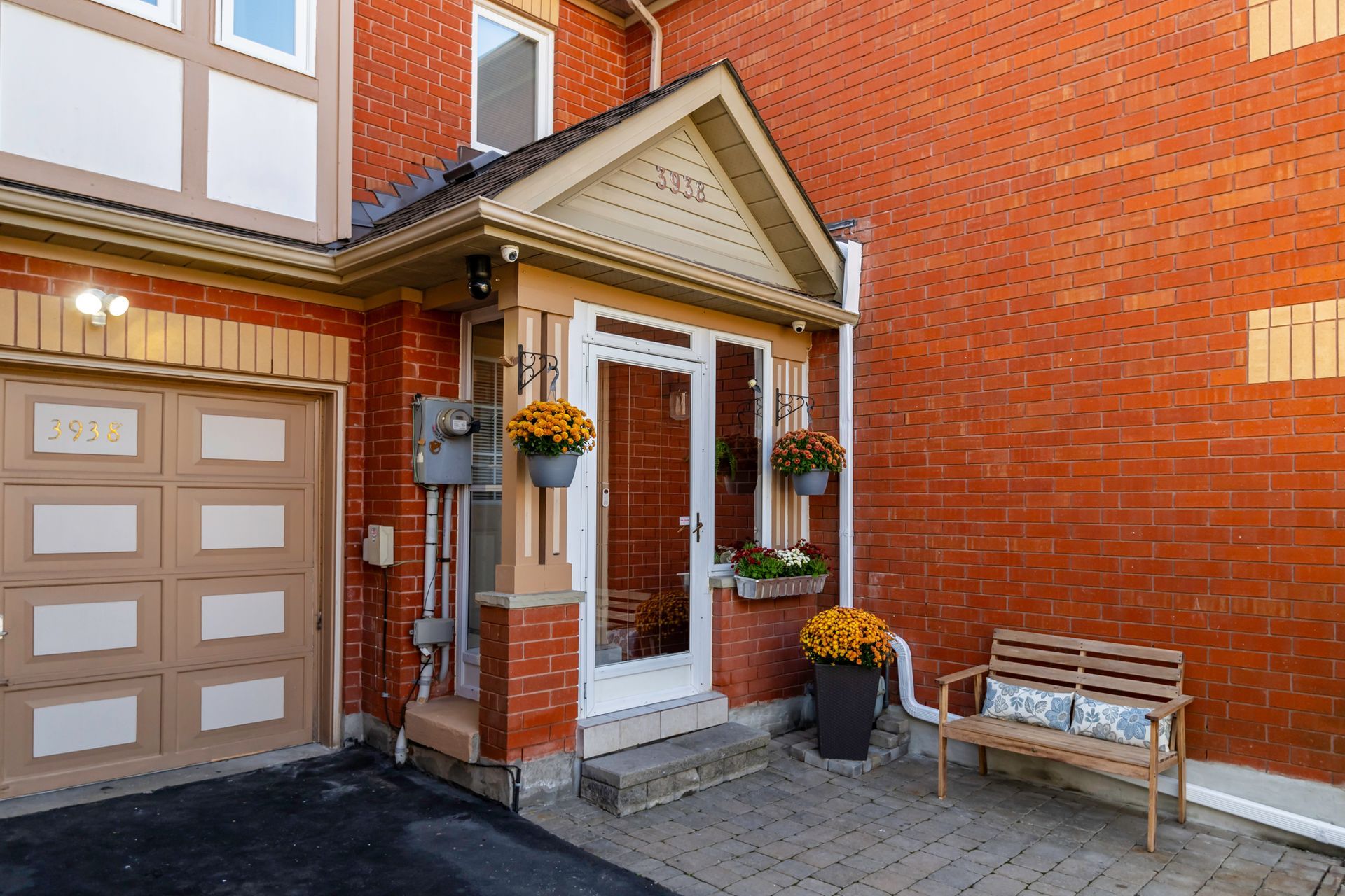 A brick house with a porch and a bench in front of it.
